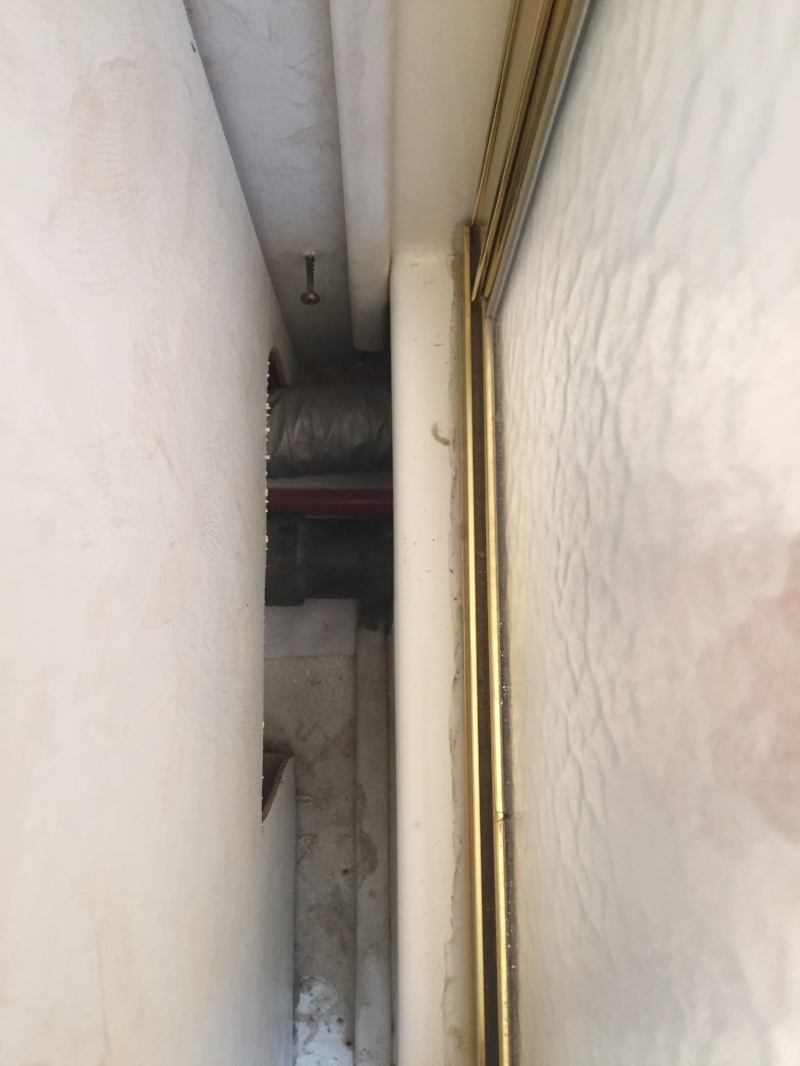 This is where our pipe was cracked. Only accessible through this 4 inch gap, and through the part of the cabinet that was cut out to the left.... (the pipe is the small red one. under the big black one.) ugh.