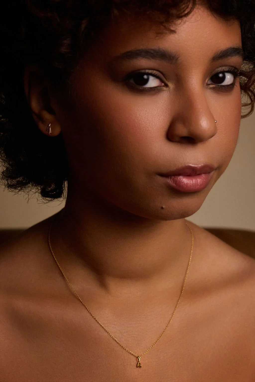 A model wears the dainty, gold seedling pendant.