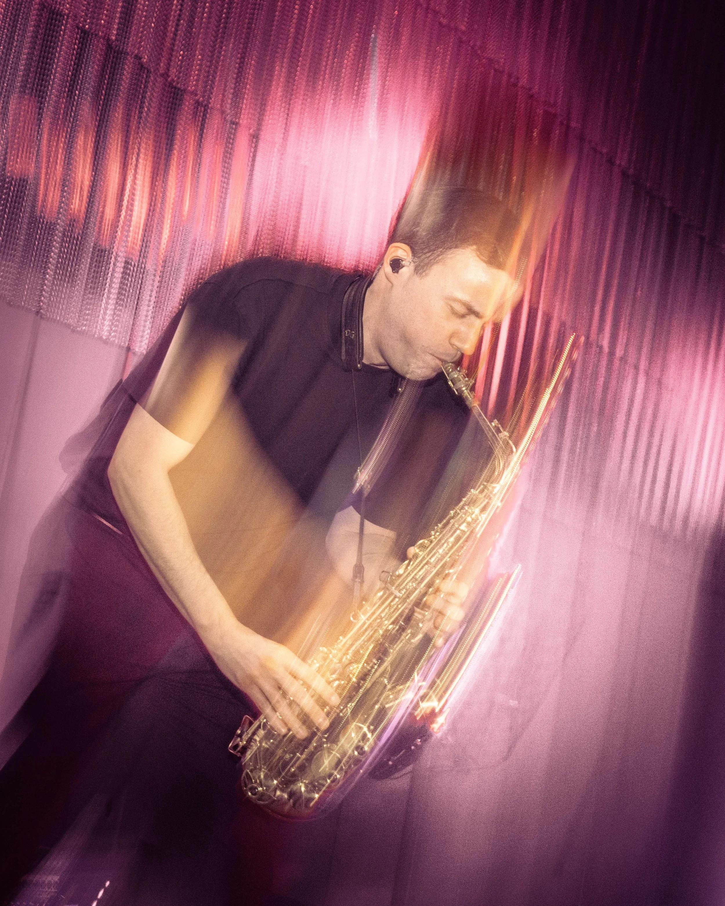 A man playing a saxophone with motion blur effects creating streaks of light and a blurred background.