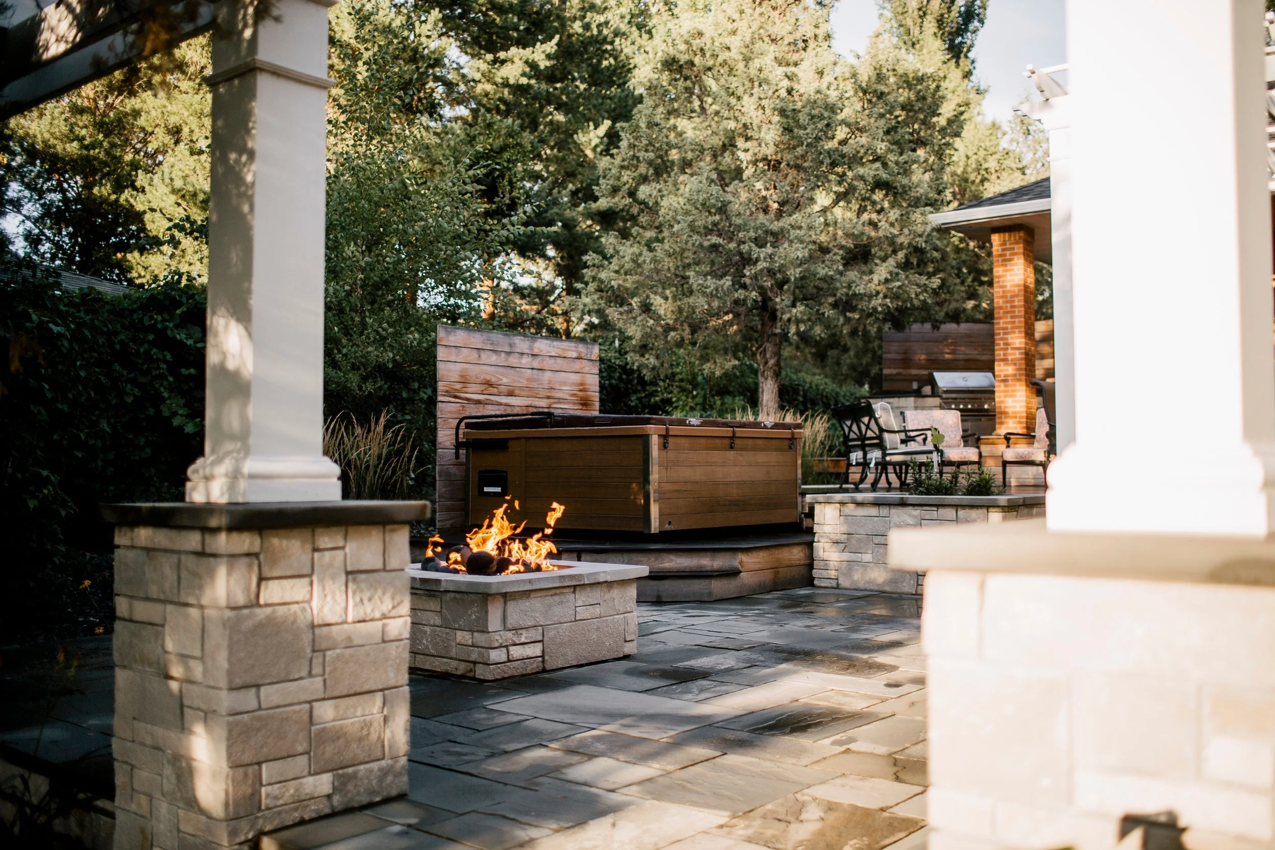 Upper deck leads to lower patio with firepit and hot tub with view to outdoor TV.