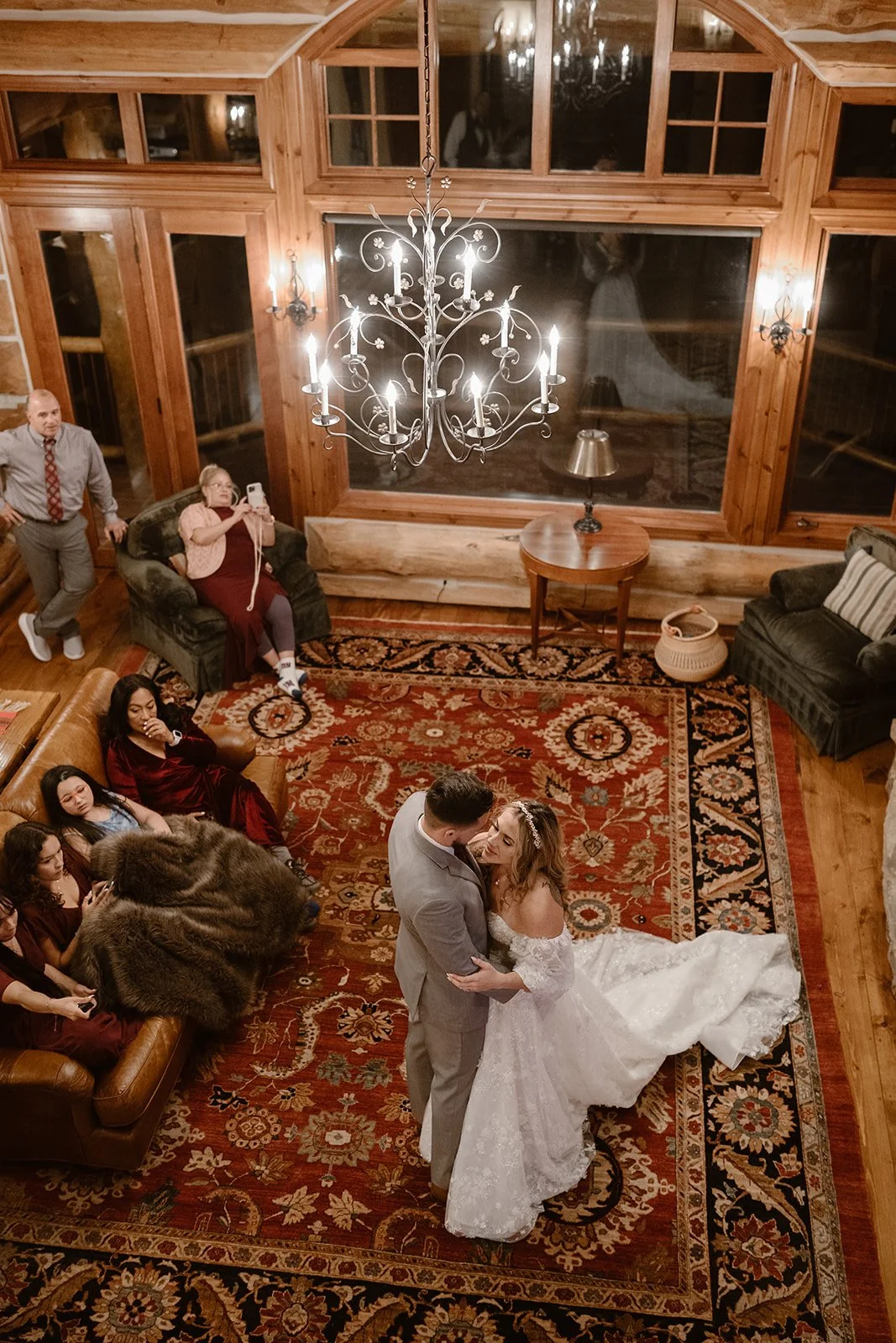 Bride and groom dance on an oriental rug at their cabin wedding reception