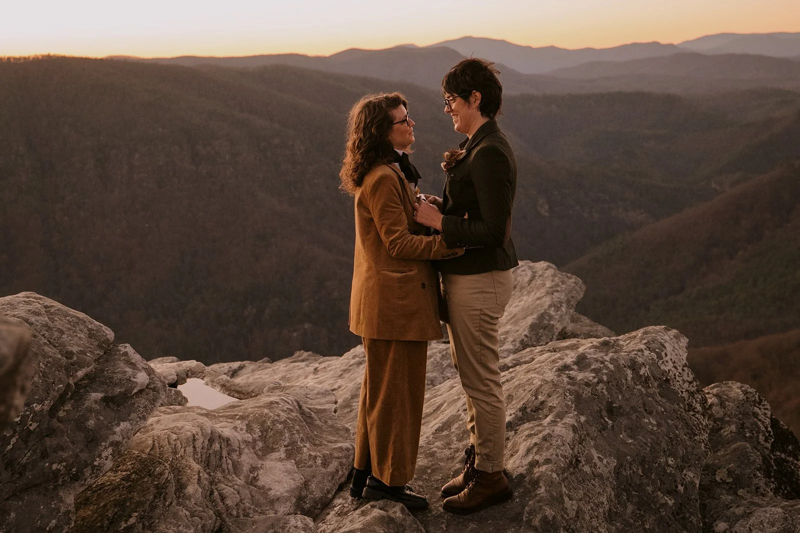 A couple embrace atop a mountain at sunset during their elopement