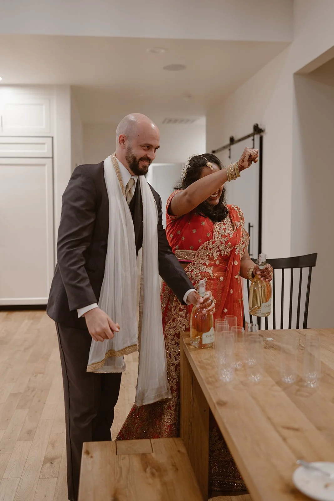 A bride and groom in traditional indian wedding attire toast their elopement reception