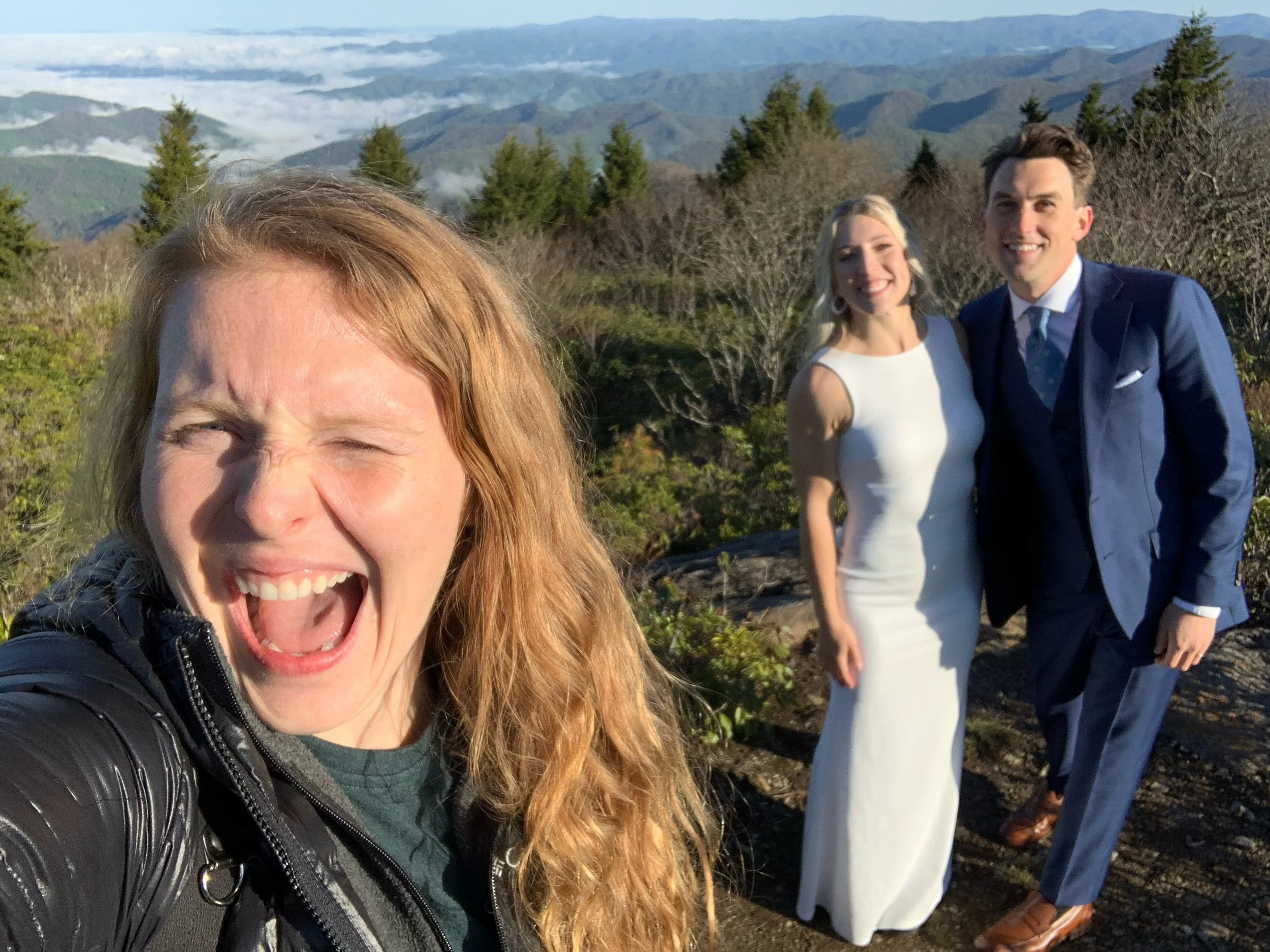 An elopement photographer takes a selfie with her couple