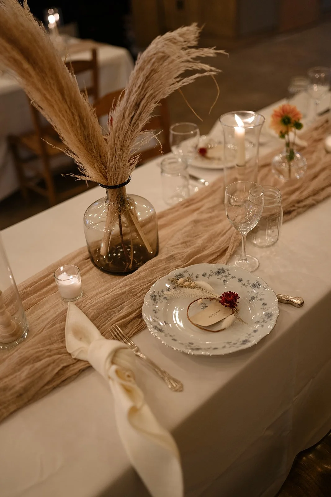 A boho rustic elopement reception tablescape is lit by candles