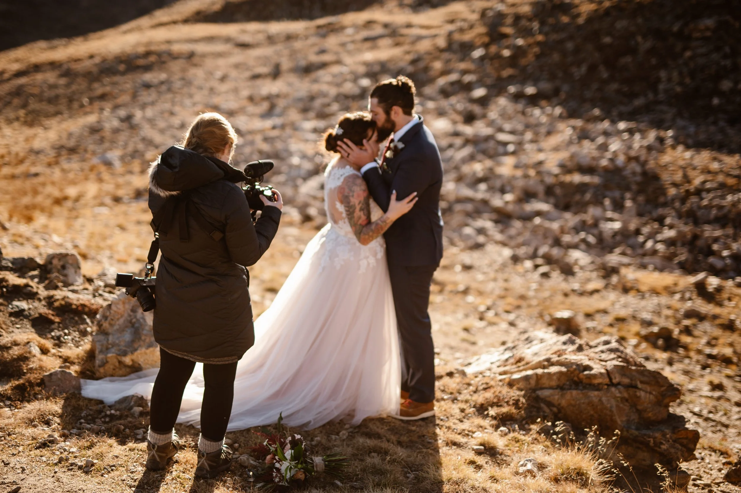 An elopement videographer captures a couple in a close embrace atop a mountainside