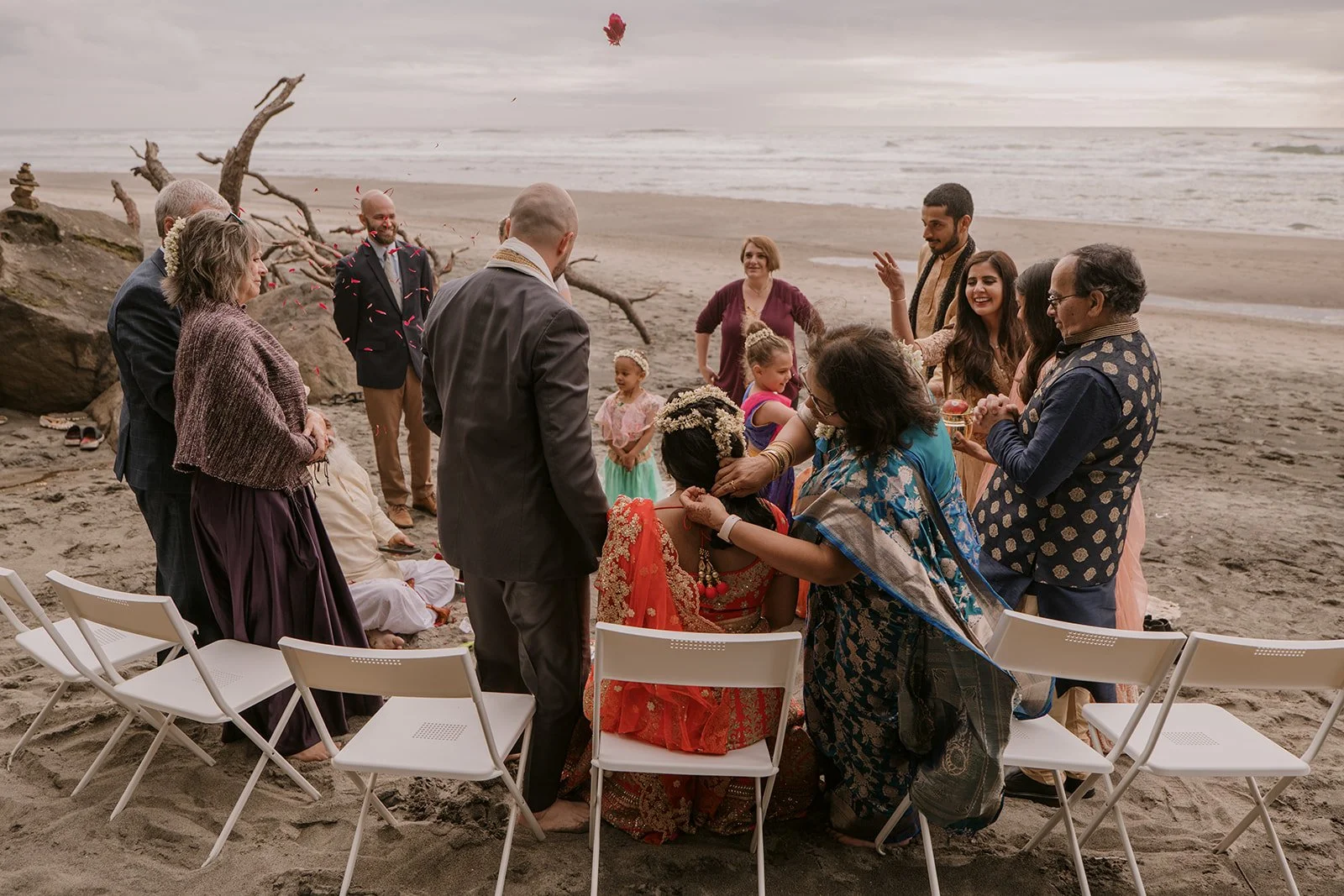 White folding chairs gather round an intimate elopement party on the beach