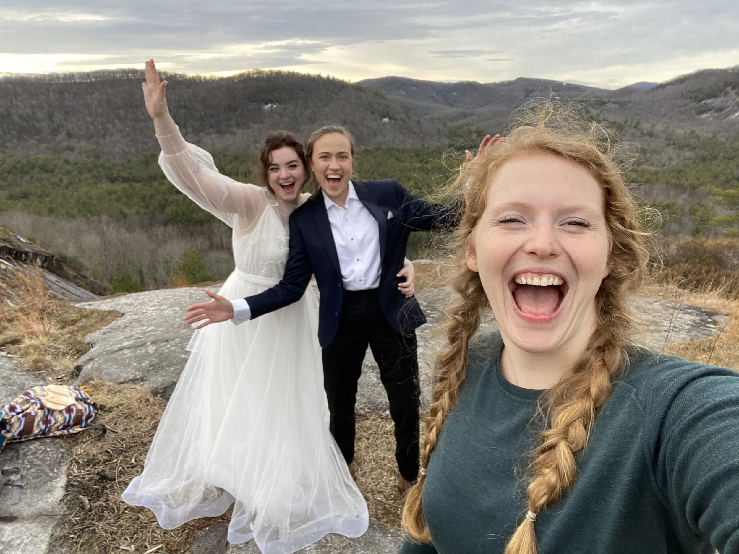 An eloping couple pose for a selfie with their female photographer