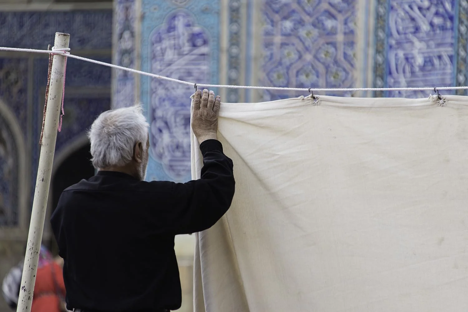 Man Hanging Prayer Curtains Outside Mosque