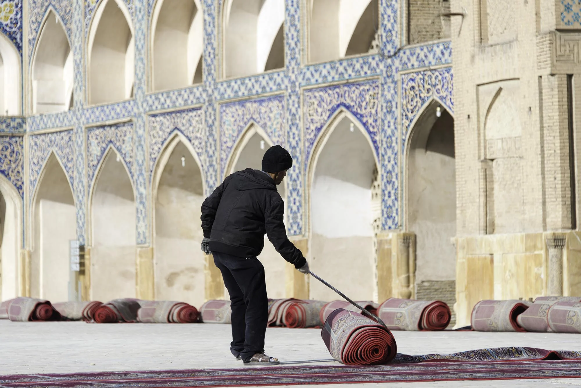 Iranian Man Unrolling Prayer Rugs