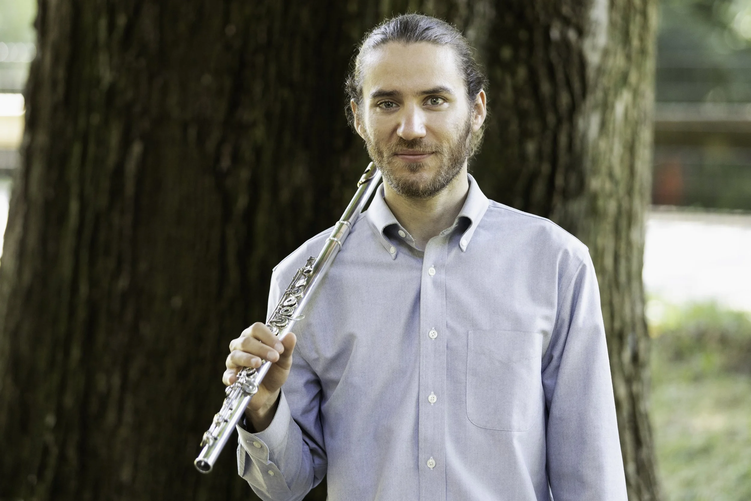 headshot of Leo Sussman holding flute in front of a tree