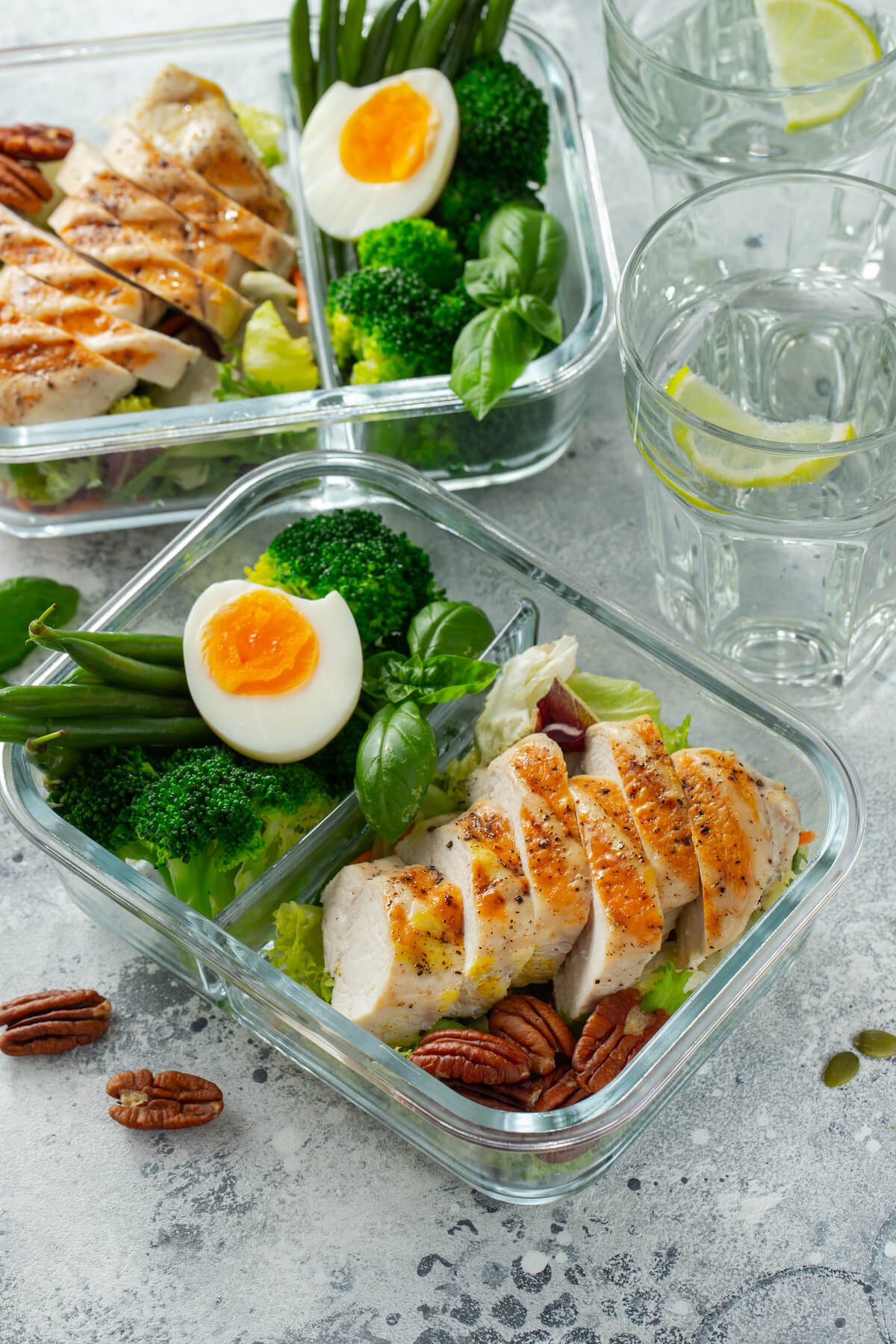 Glass meal prep containers with fresh chicken and eggs
