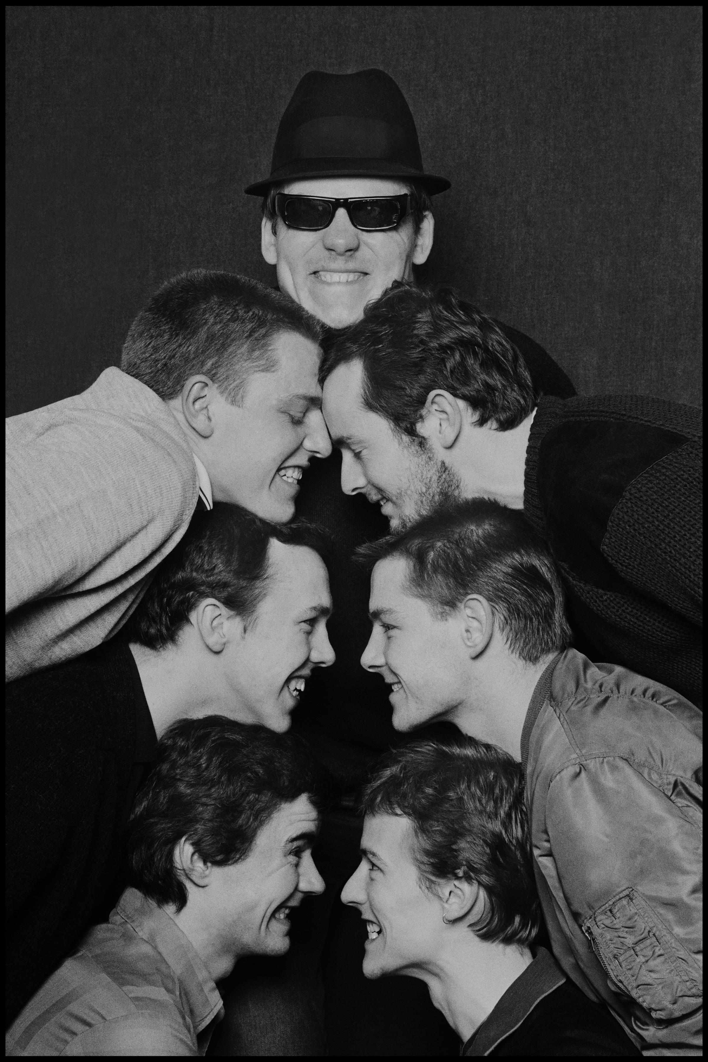 Madness - Glasgow 1980 Because I worked for the Specials I knew the chaps in Madness from the Two Tone Tour, but I took few photos as they had their own favourite photographers and I did not want to intrude. Then they quit the Tour and were replaced by Dexy's Midnight Runners, another great band from that era, with a leader who had more passion than anyone I had ever met. When Madness subsequently went out in their own tour I was commissioned to photograph them. To be honest anyone could have done these guys, posing came naturally and they had a cohesion that made for great photos every time. But instead of the action packed photos they were used to doing I decided to simply take a photo of their heads, this picture was done in a couple of minutes backstage in Glasgow. Not long after this I ended up on a train to Oxford with them, I was just going to their show and had no cameras with me. I got talking to Suggs and Kennedy's assassination came up, he had little recollection of an event that causes everyone from my generation to remember exactly where they were when they heard the news. Then it dawned on me, Suggs was the first person I knew who was born in the 60's, not the 40's or the 50's. I realized that he was part of the next generation, and at the age of 27 I felt old for the very first time.