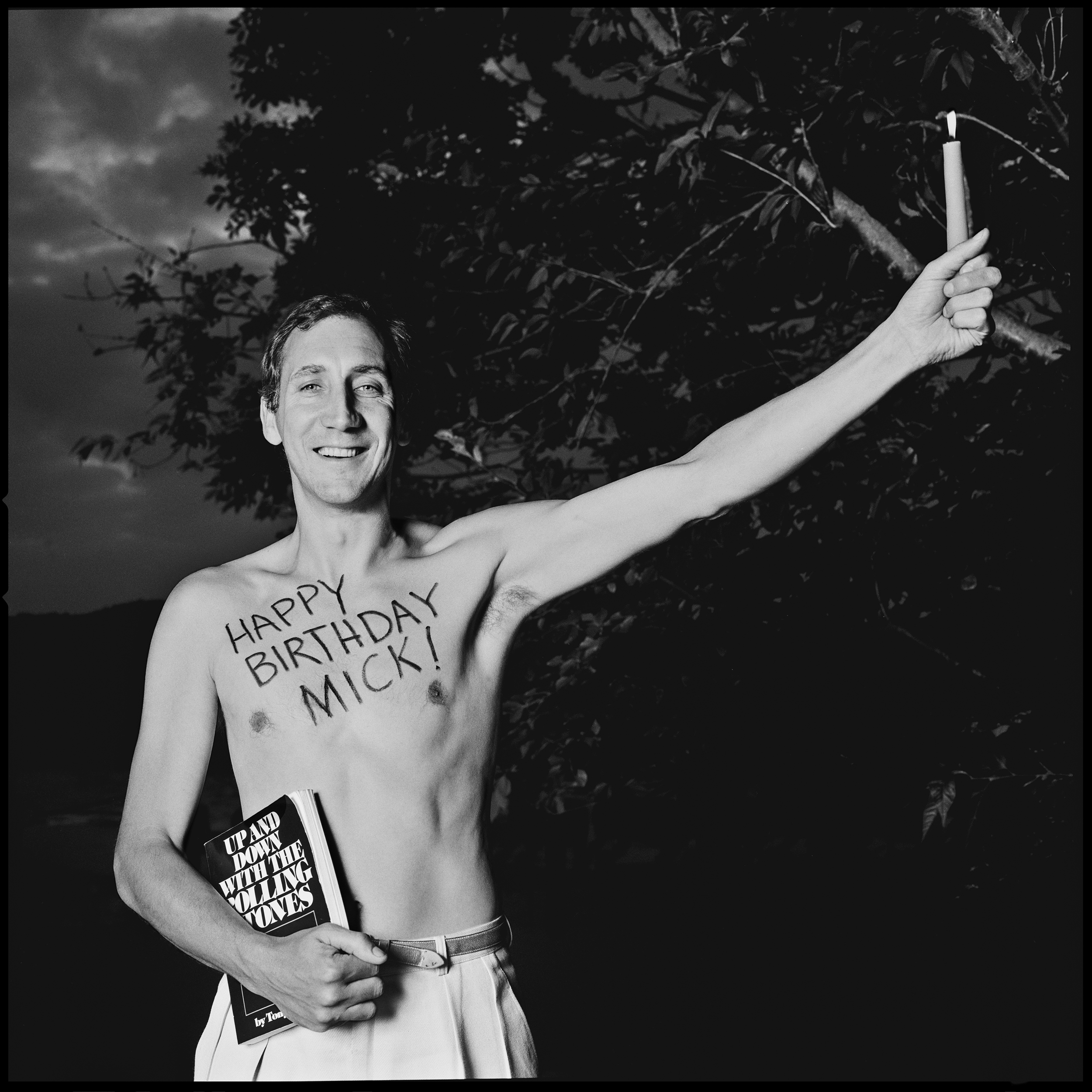 Pete Townshend as the Statue of Liberty 1983 A long time ago, in a galaxy far from here, Mick Jagger celebrated his 40th birthday, and Pete Townshend wrote an OpEd in the Times to celebrate this monumental event. Unbeknownst to Pete, Jaan Wenner had purchased the piece for Rolling Stone and we were dispatched to take a suitable photo. Pete has always done anything we asked and it was decided that he should become the birthday card, and as the photo was for America the idea of imitating the Statue of Liberty came up. We gave him a candle to hold in one hand, and a copy of Robert Greenwood's book, "Up and Down with the Rolling Stones" was placed in his other hand. To complete the card, Starr wrote the message "Happy Birthday Mick" on Pete's chest with lipstick. By this time the light was going down quickly so we used fill in flash and took the photo in the garden of his house in the country. The result is a happy, and fun filled photo. Perfect for a birthday card from one mega Rock Star to another.