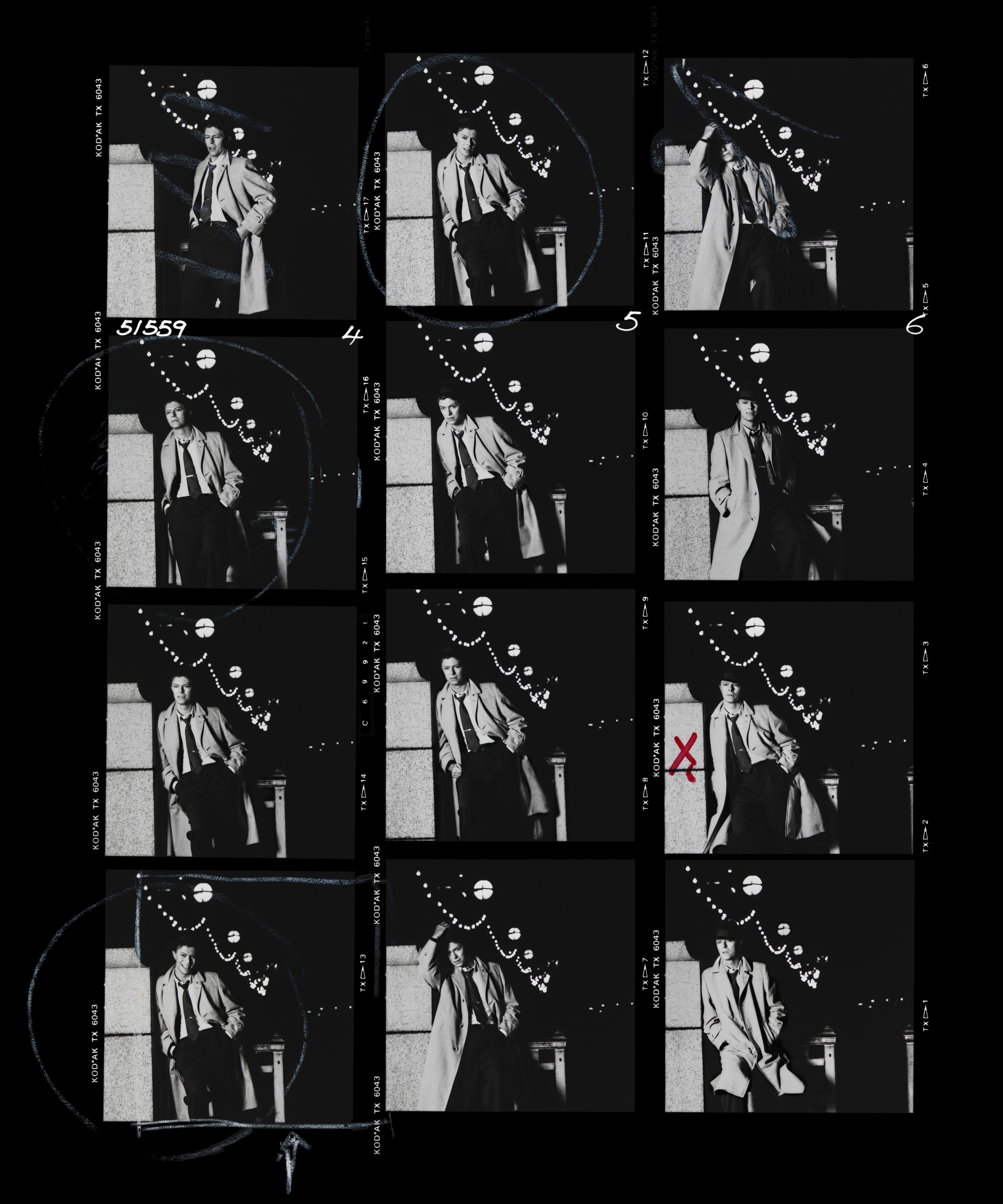 Absolute Beginners Contact Sheet 1986 David Bowie is one if the easiest people to work with, he's so good in front of the camera that you can do a record cover in a single roll of film. When you are on a film shoot nothing endears you to the Director more than the ability to shoot fast. Everything was pre-lit and tested beforehand, all it needed was for David to step into the frame and pose for three minutes. Contact sheets can tell you a lot about both photographer and sitter, the twelve frames on a roll is now a thing of the past but back then it was the order of the day. When you have to hand over the sheets to the publicist you never know what you will get back from the artist, sometimes with Rock Stars only a single frame from a dozen rolls is marked, sometimes they approve three or four, but that is not the case here. In the right hand strip you can see a small X, this was the choice of David's management, safe as houses, but also kind of boring. On the whole page you can see exactly the way David marked it up, excluding only two frames as a bad photo, ignoring seven more frames as they were OK but not great. Then he has circled three of the frames including 4C, the one where he is smiling. The Art Director then marked a square around that same photo. I was very happy David and the AD chose it, but this surprised everyone who worked for him as he has never, before or since, smiled on a record cover.