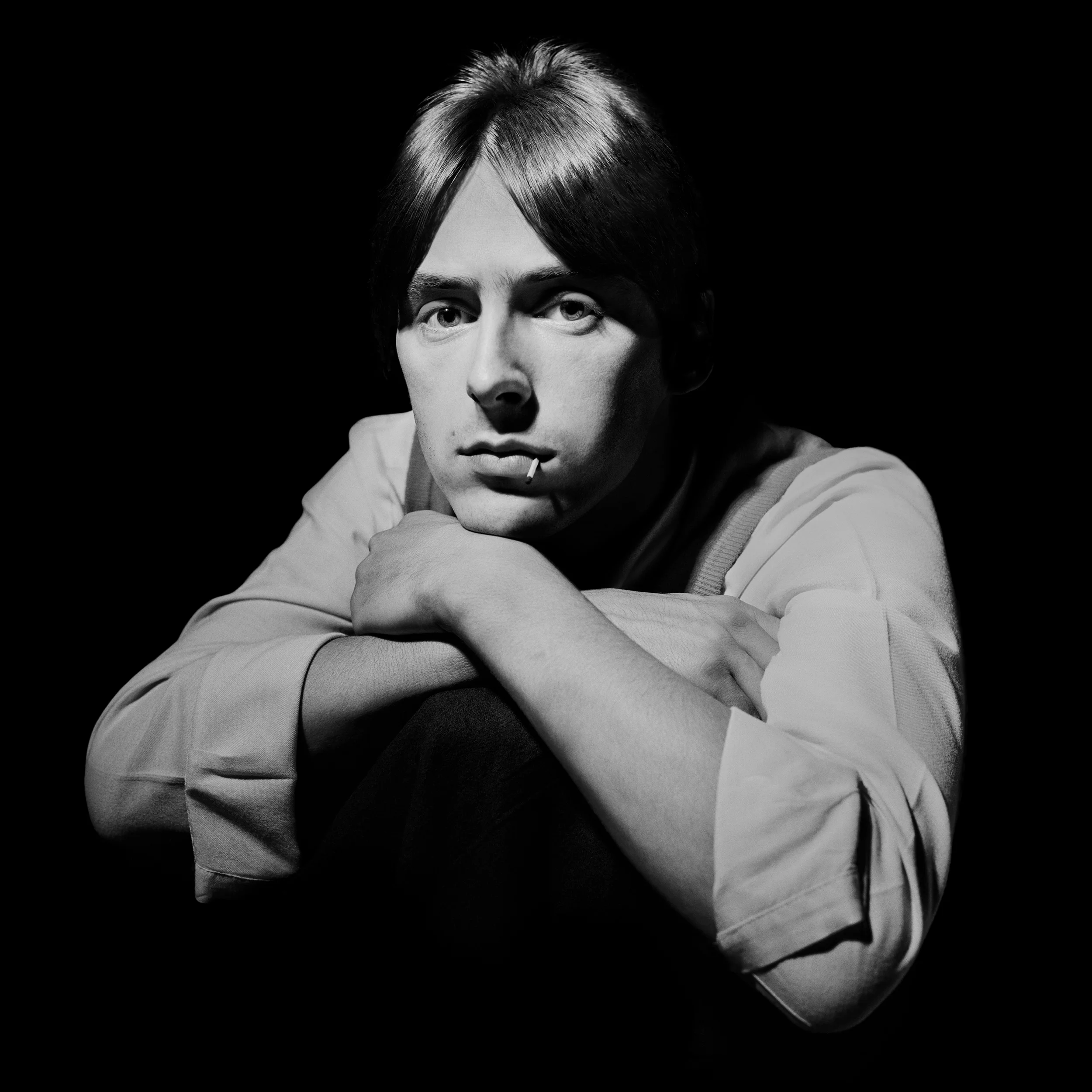 Paul Weller - The Face 1981 Whilst Terry Hall never appeared to smile, he was certainly not miserable, he just saw no need to smile, if you asked him to he did, albeit in a very minimalist fashion. The same was not true of Paul Weller. I remember this shoot well, it was a cover story for the Face, he was wearing a bright red vest, a clean white shirt, and his hair was a perfect copy of Stevie Marriott. You could certainly direct Paul, it did not do you much good however. All you got was the look, a stare that questioned his reason for being there, that this was part of the job, that you would never see below the surface. Being for the cover it needed to be good, I tried everything to get some kind of look on his face, every angle failed, nothing brought a smile to his face, nothing I said caused any change in him, the photo needed something and I told him so. Out of his pocket he produced a box of matches, he put one in his mouth and the picture somehow now had a life, he moved it around slightly between frames, as if it were an important prop. His face is exactly the same in all the pictures, the position of the match governs the choice, yet somehow there is something here, a flicker of interest in his eyes, but you have to look really hard to see past the persona he has always projected, that of Paul Weller, leader of the Jam, leader of the Style Council, and now the Godfather of Pop, I'm amazed he has lasted this long.