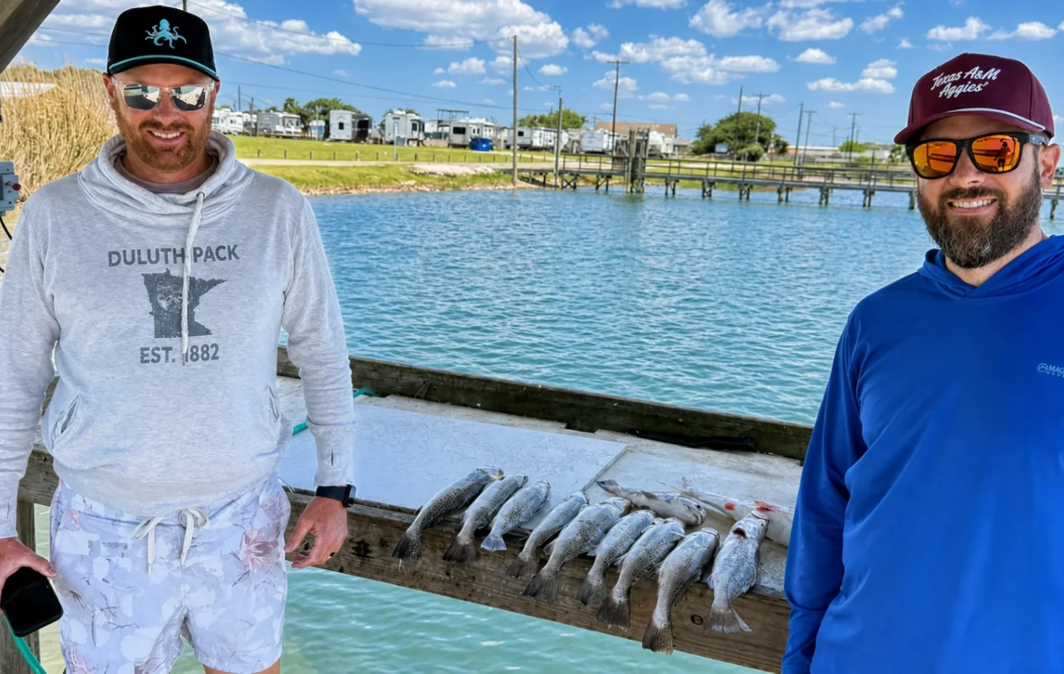 Two anglers standing by a dock rail with a fresh catch after a Rockport bay fishing trip