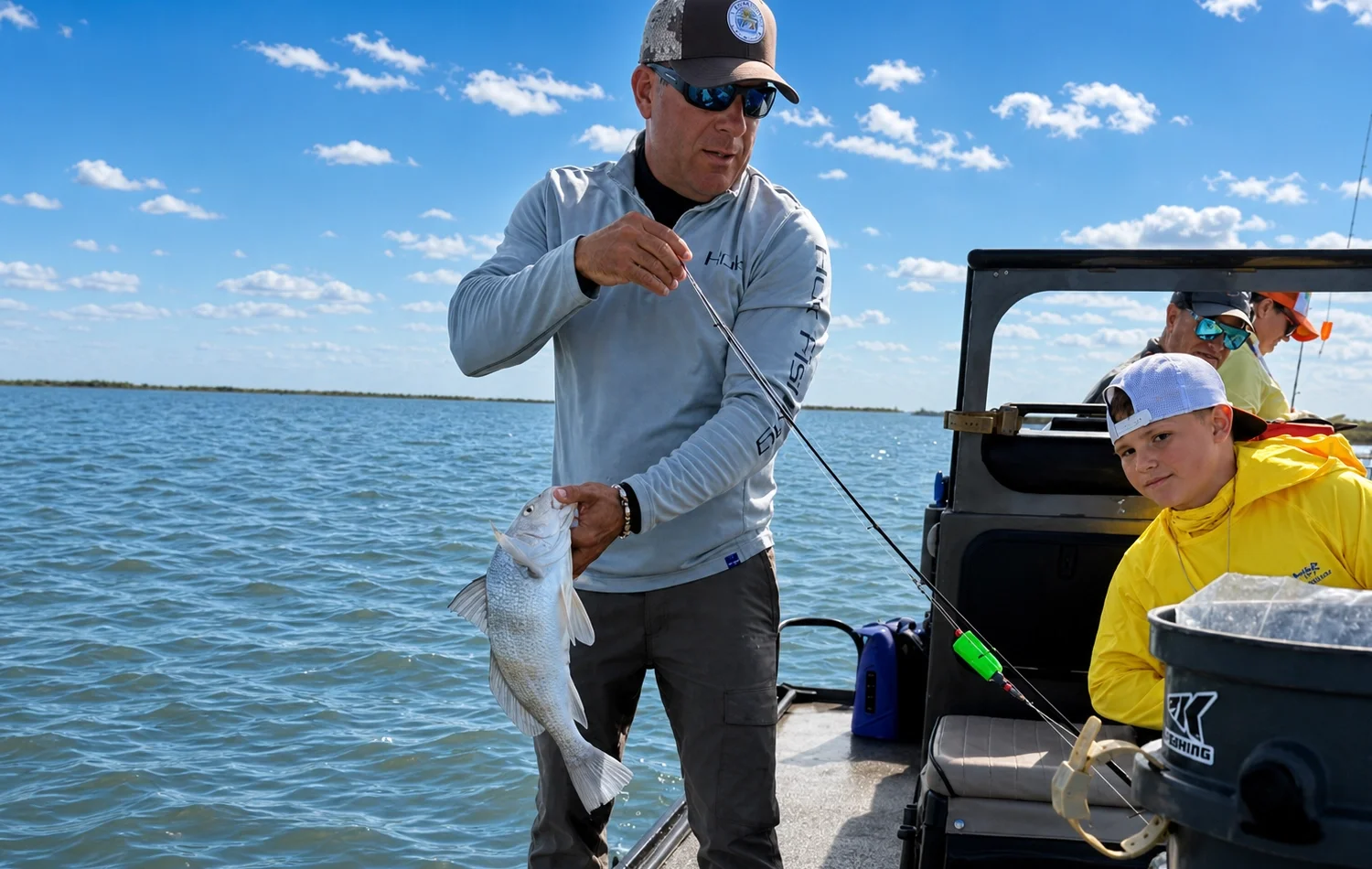 Captain helping display a fish on a family-friendly Rockport bay fishing trip with kids on the boat