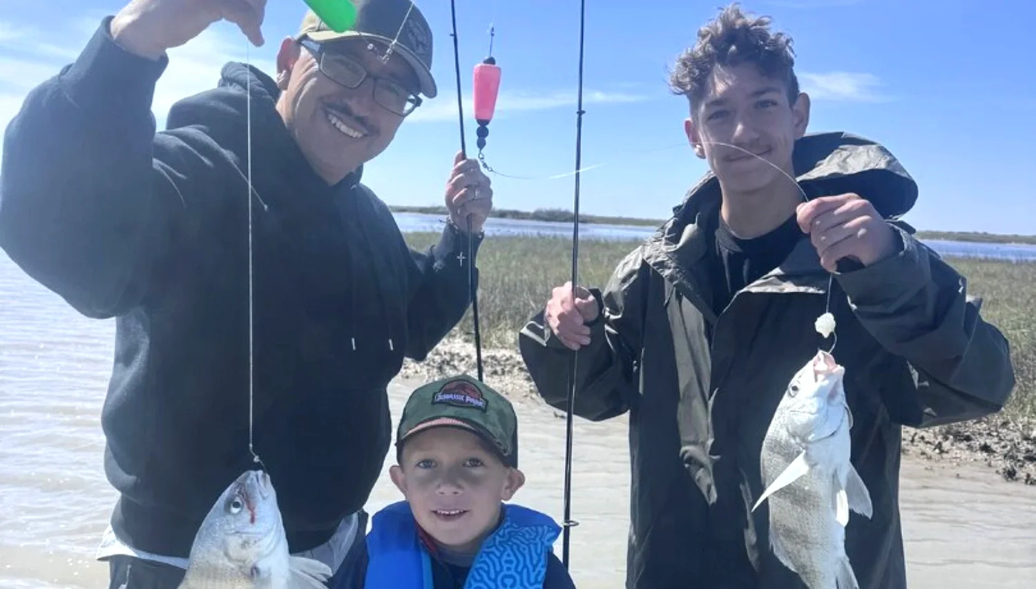 Family showing their catch on a kid-friendly Rockport bay fishing trip