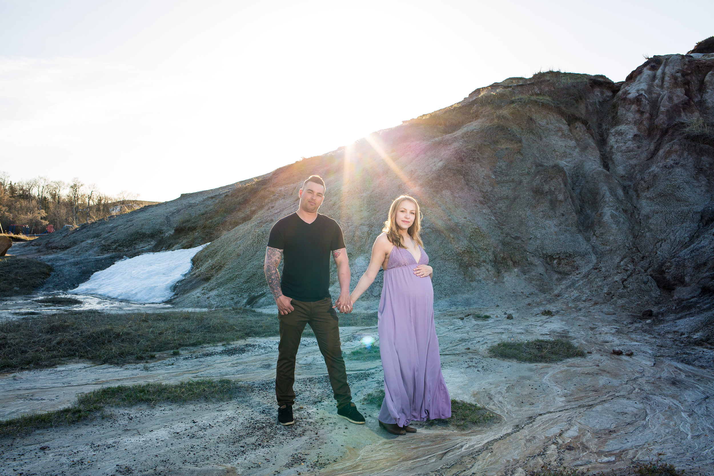 couples maternity holding belly outdoor mountain in a purple dress holding hands
