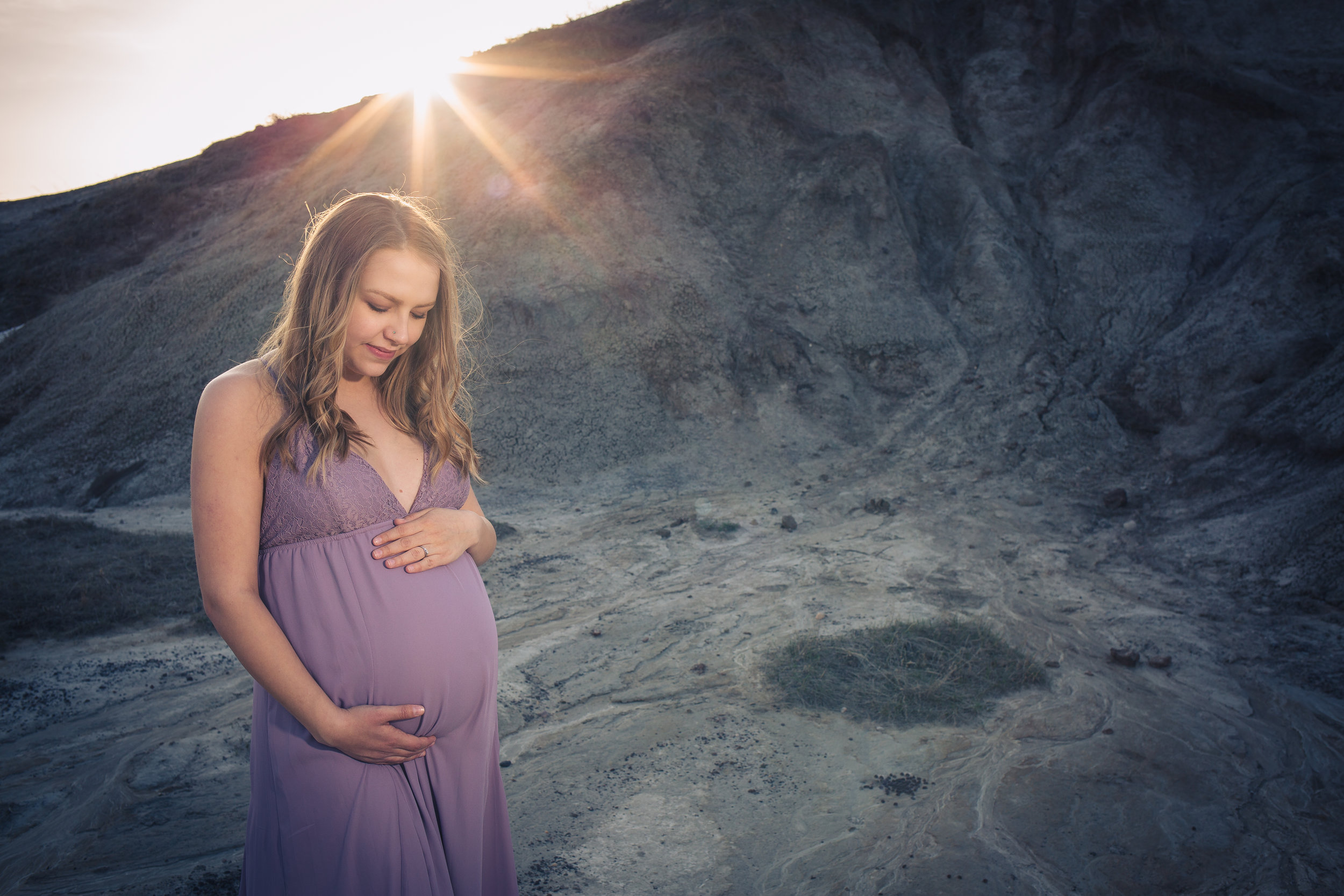 maternity holding belly outdoor mountain in a purple dress