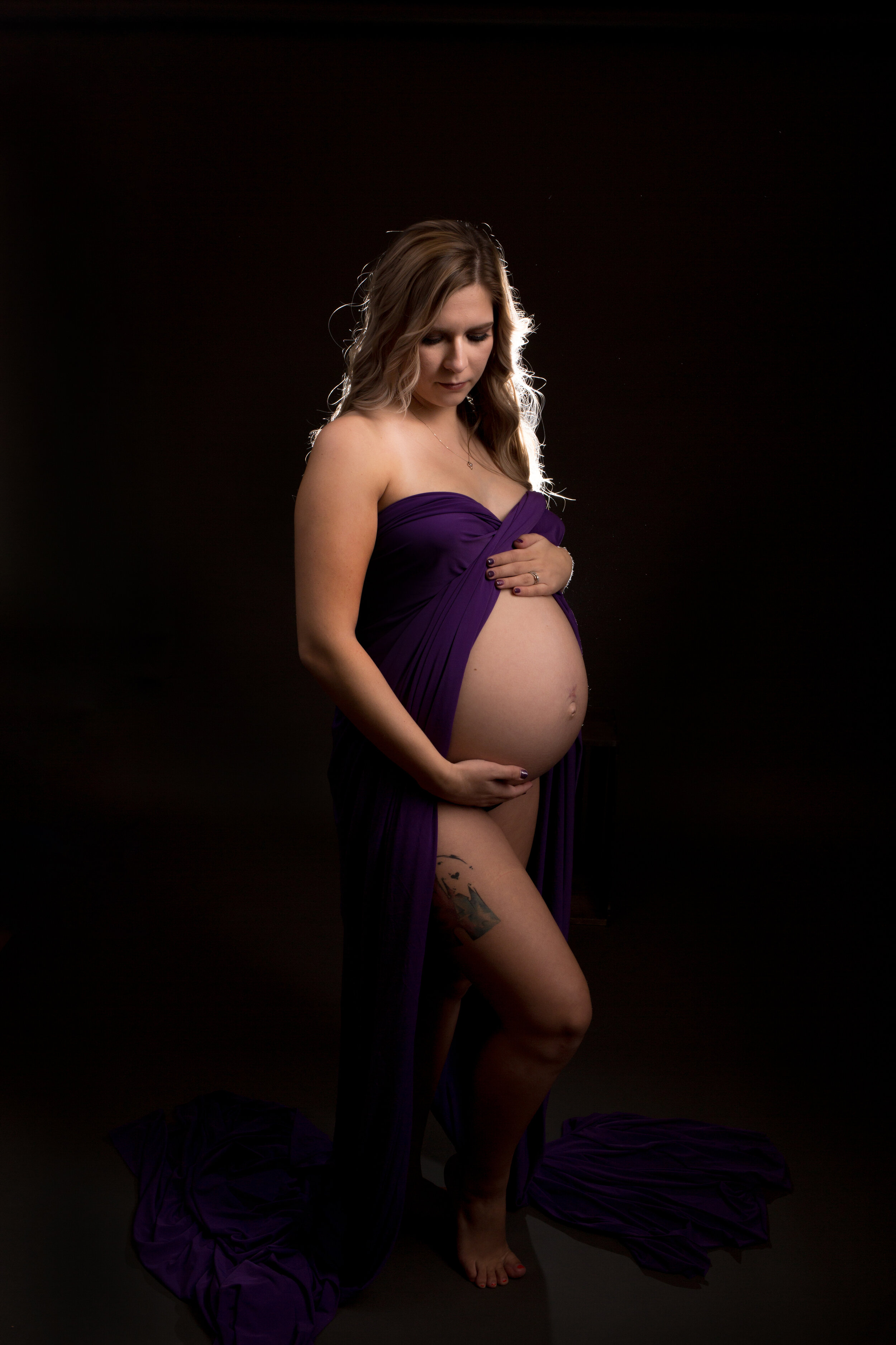 maternity boudoir silhouette glamour holding belly in purple dress