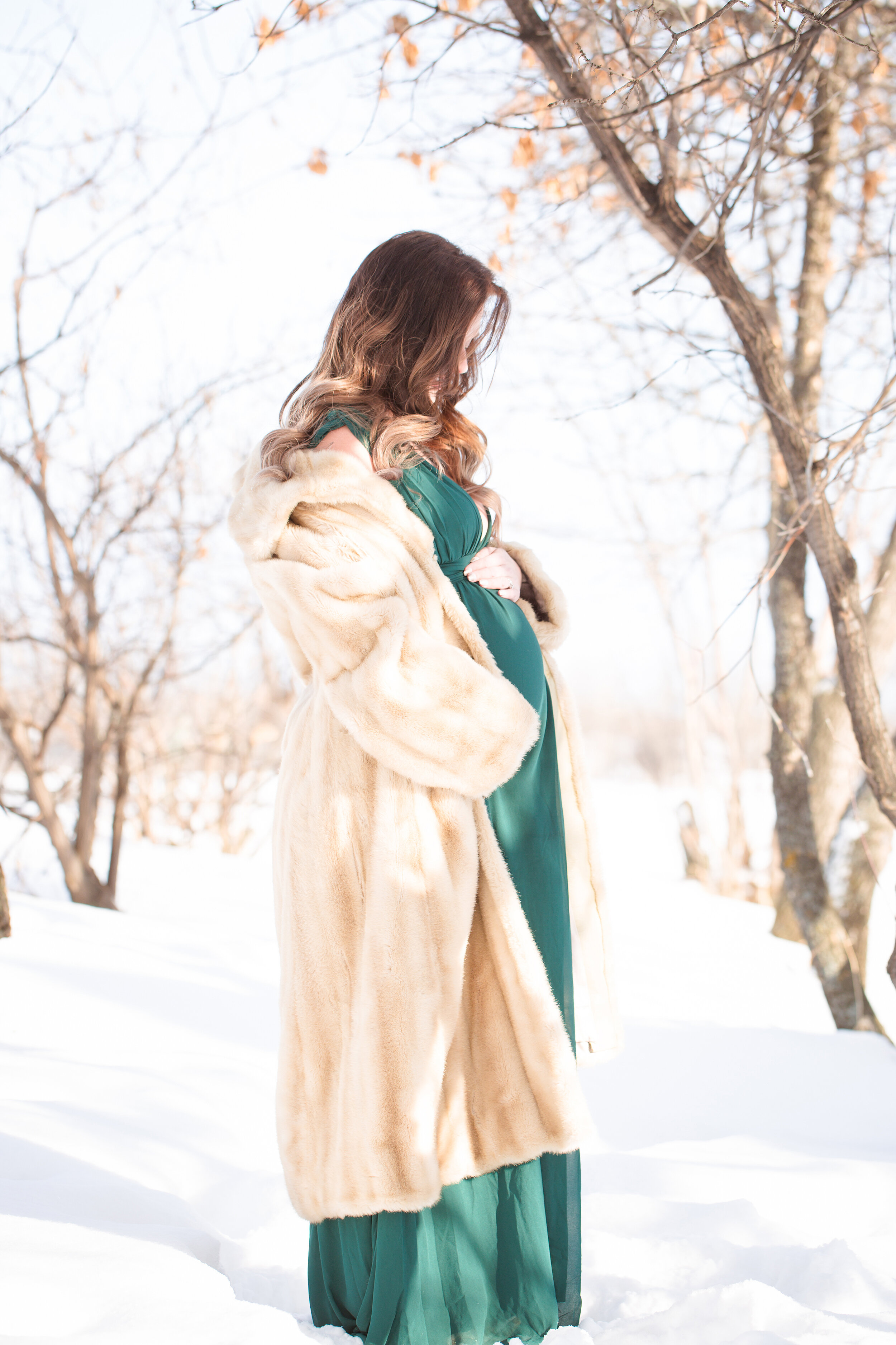 Maternity holding belly in the winter snow fur coat and holding belly