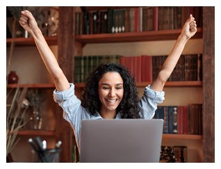Photograph of woman raising arms in triumph while playing computer game
