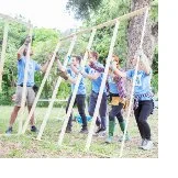Photograph of group of volunteers helping raise a wall of a house construction