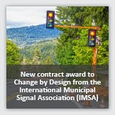 Landscape photograph of roadway next to temporary traffic signals,  overlayed with foreground text reading New contract award to Change by Design from the International Municipal Signal Association (IMSA).