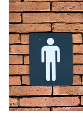 Photograph of male pictograph sign on brick wall in front of restroom