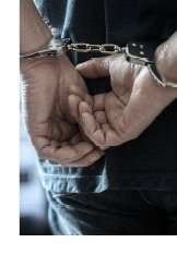 Close-up photograph two wrists handcuffed behind the back of a man.