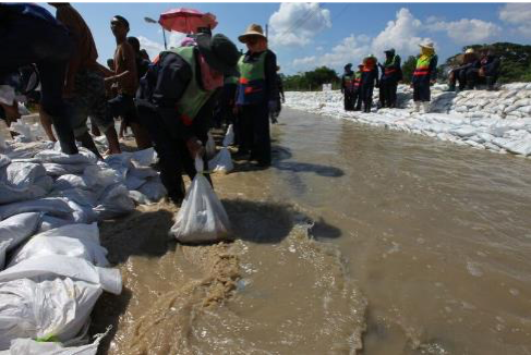 Volunteers and members of the Royal Thai Army, military police, fill and place sandbags to redirect flooding in the northern Sai Mai district in October 2011. (Credit: Cpl. Robert J. Maurer via Wikimedia Commons) 