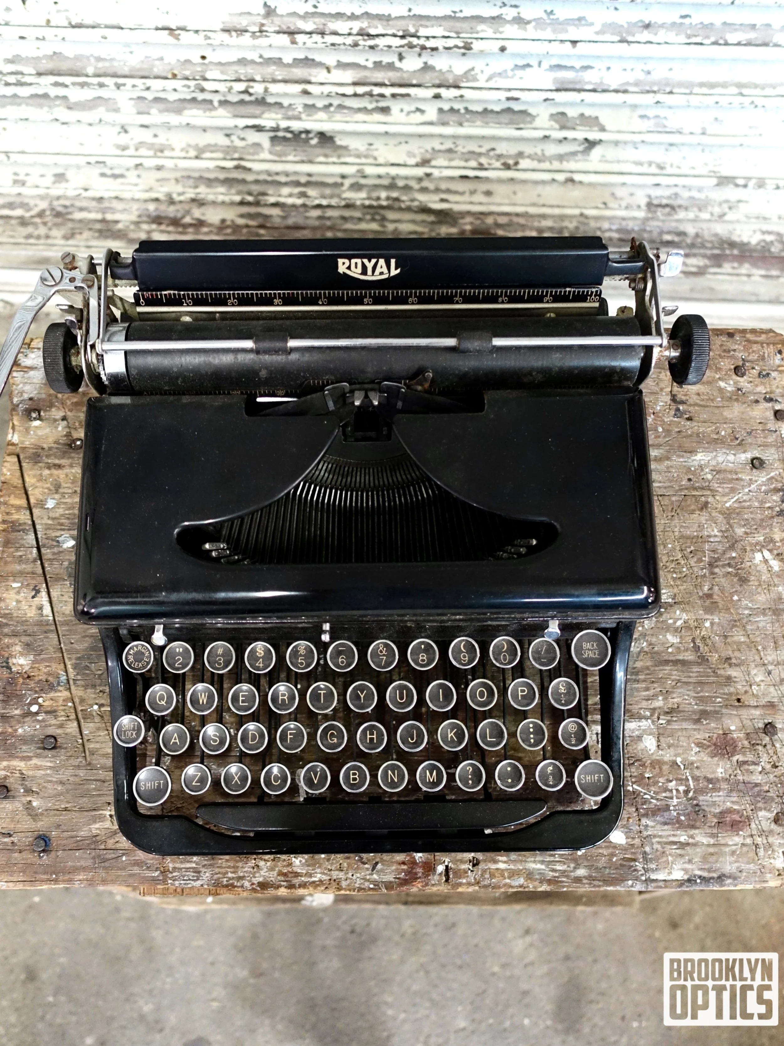 A vintage black Royal typewriter with round keys on a rustic wooden table.