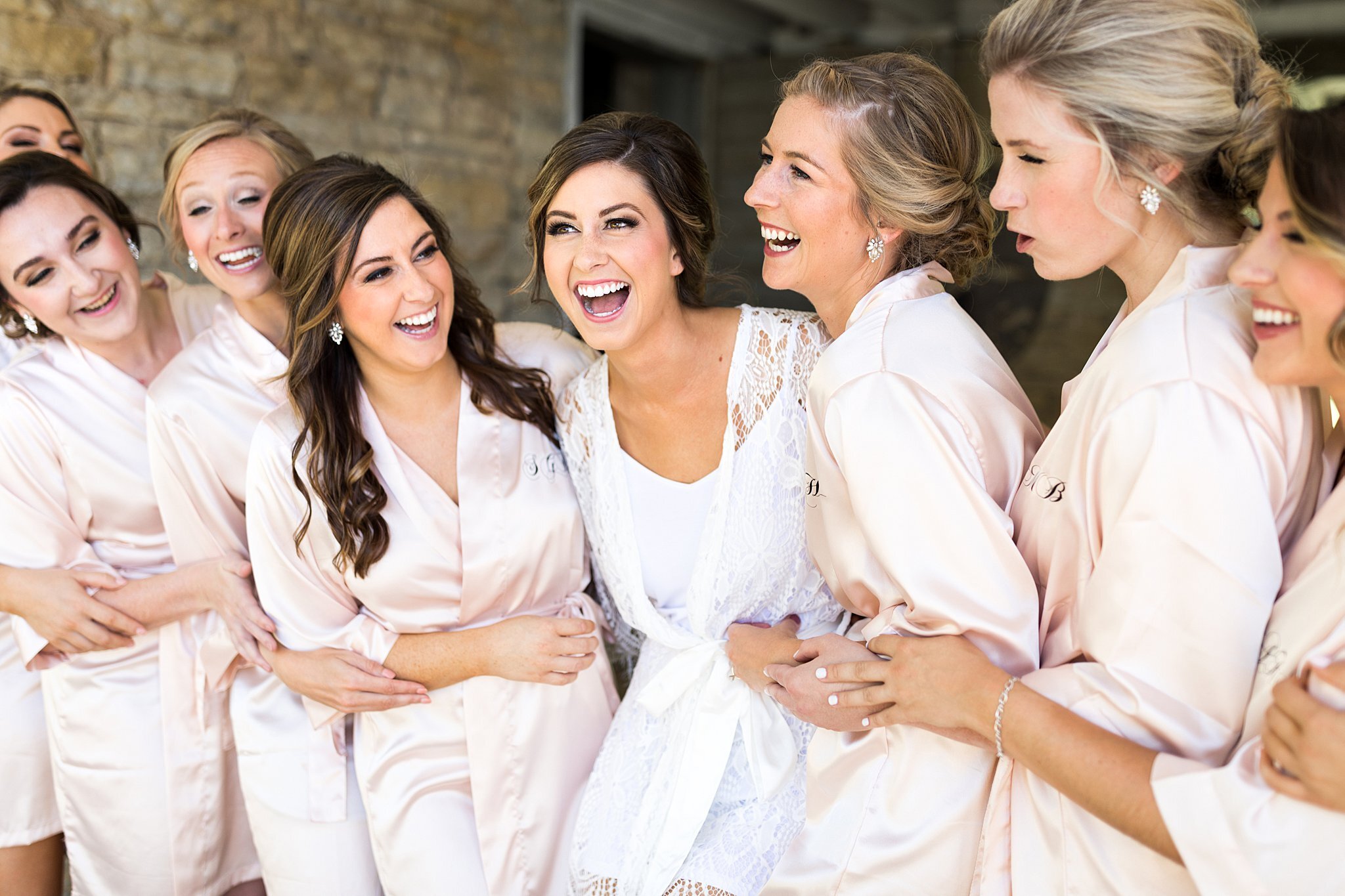  Bride and bridesmaids laughing in getting ready outfits. 