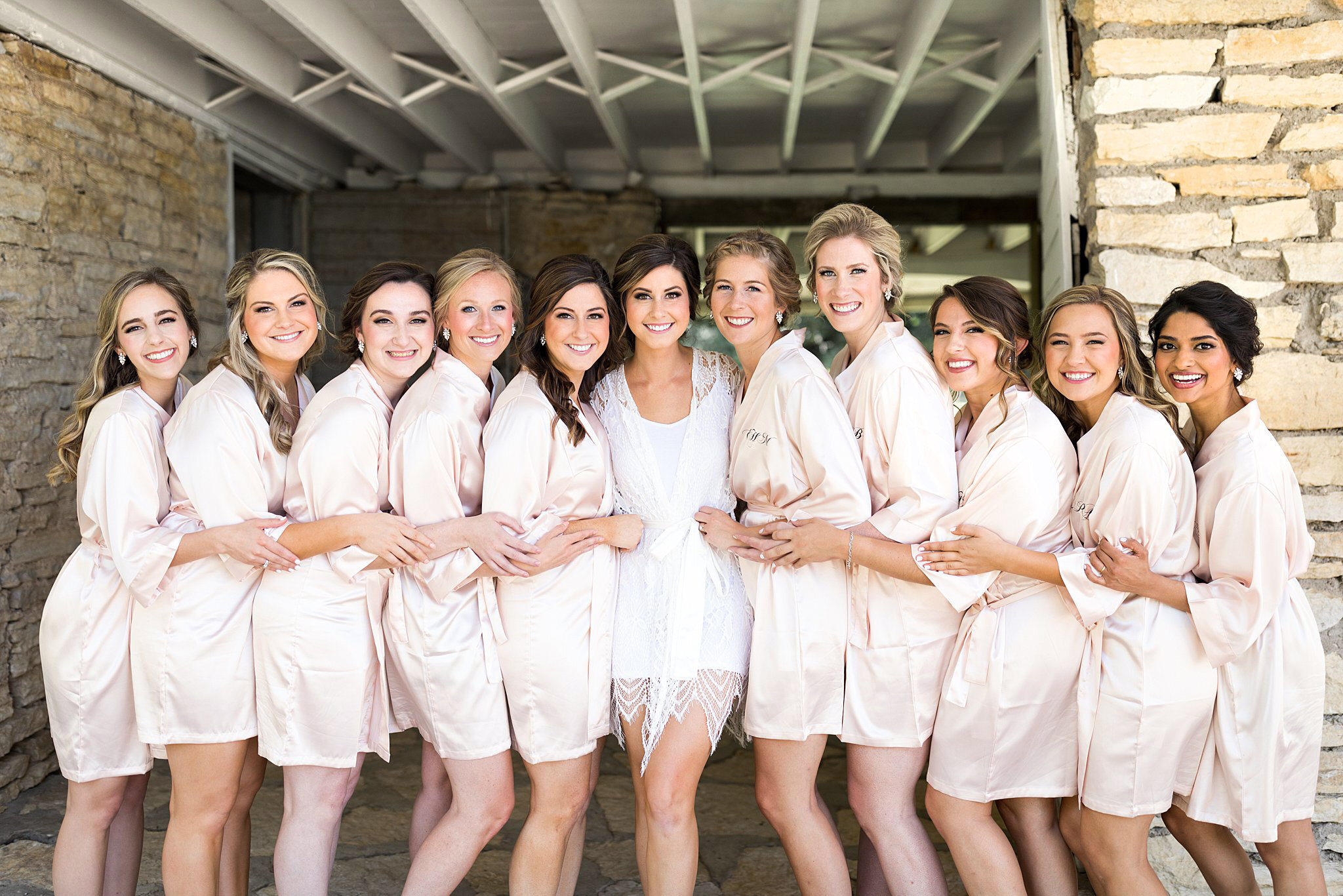  Bride and bridesmaids in getting ready outfits outside Mayowood Stone Barn. 