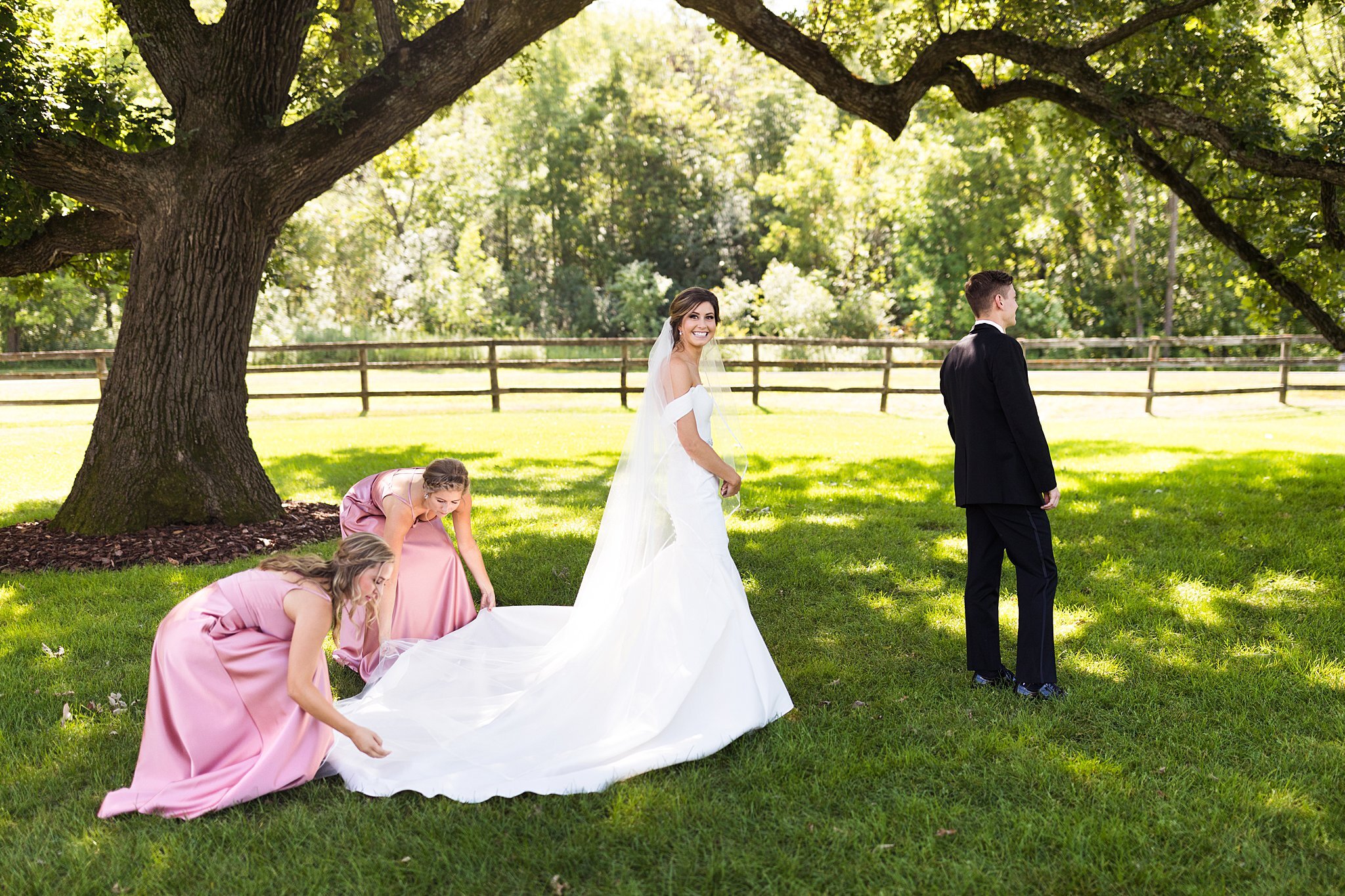  Bridesmaids laying out bride's wedding train before first look with groom. 