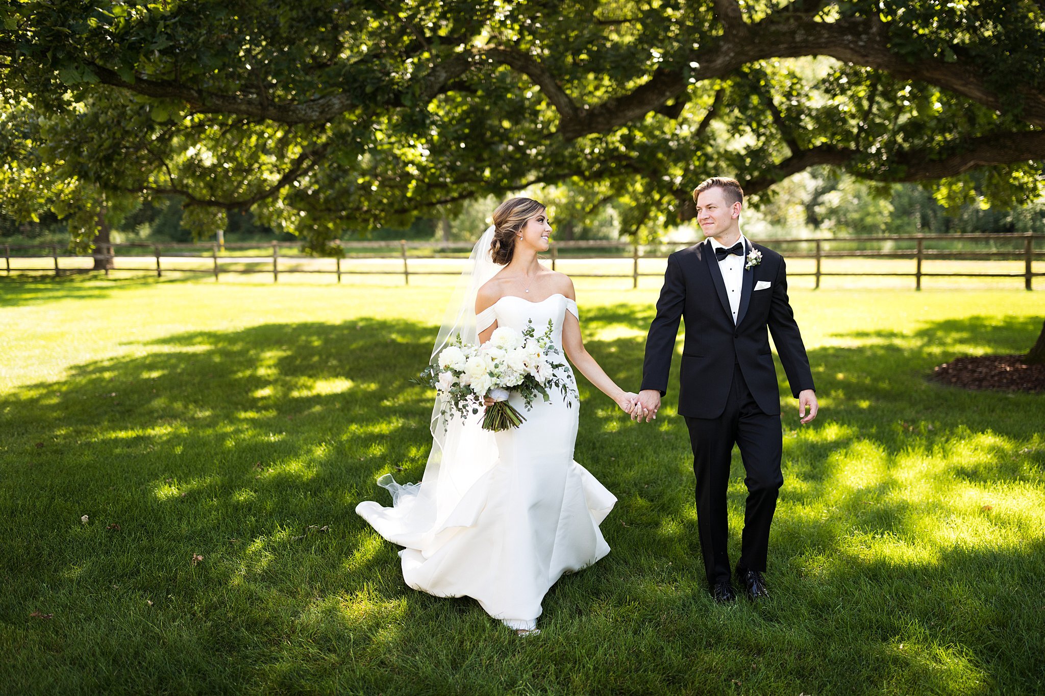  Bride and groom walk under Mayowood Stone Barn oak tree. 