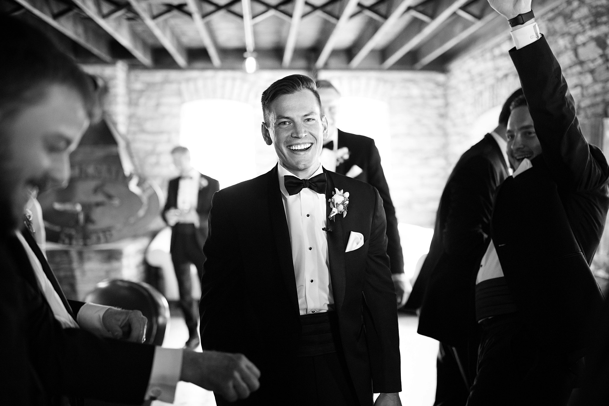  Groom smiling surrounded by groomsmen. 