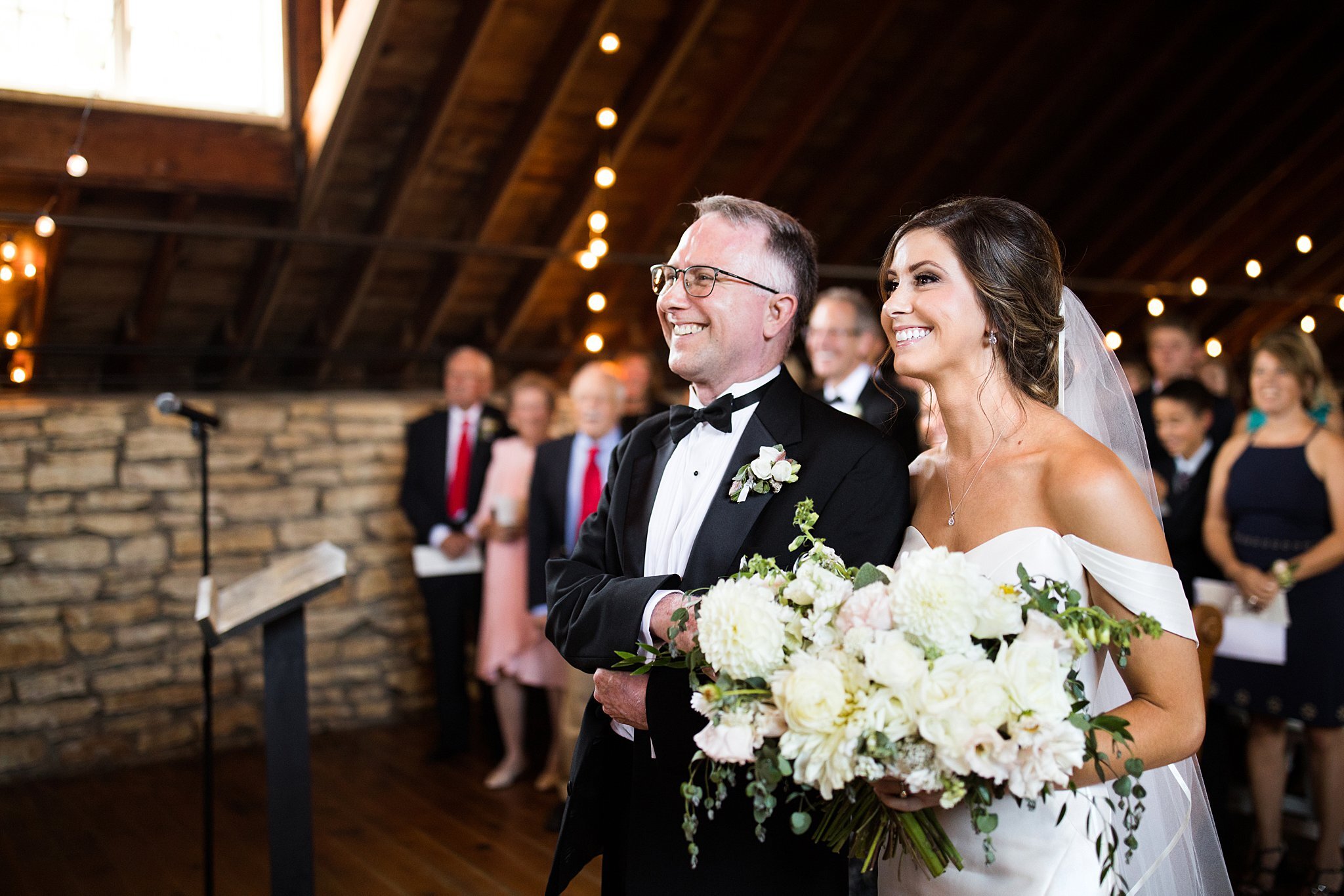  Bride and her father with large smiles walking down the aisle. 