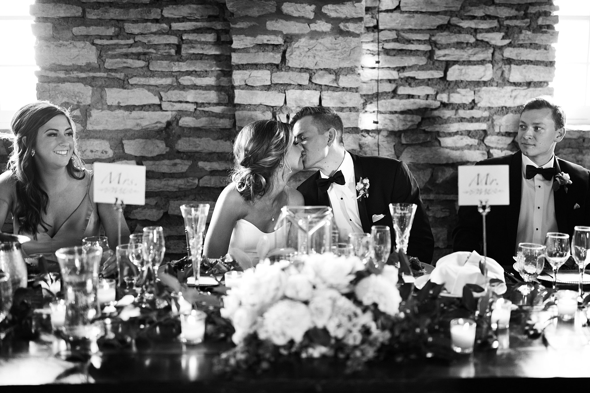  Bride and groom kissing at head table during reception. 