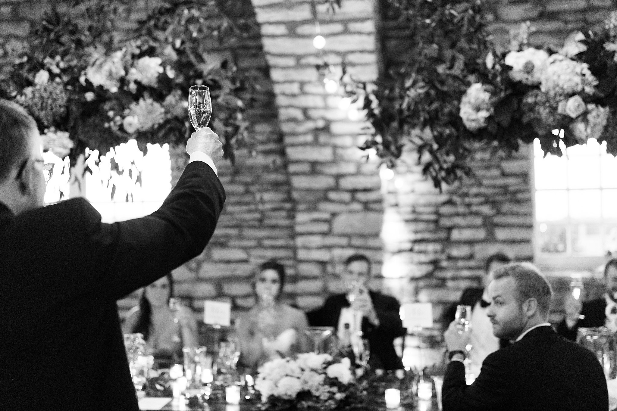  Man on microphone provides toast to bride and groom at head table. 
