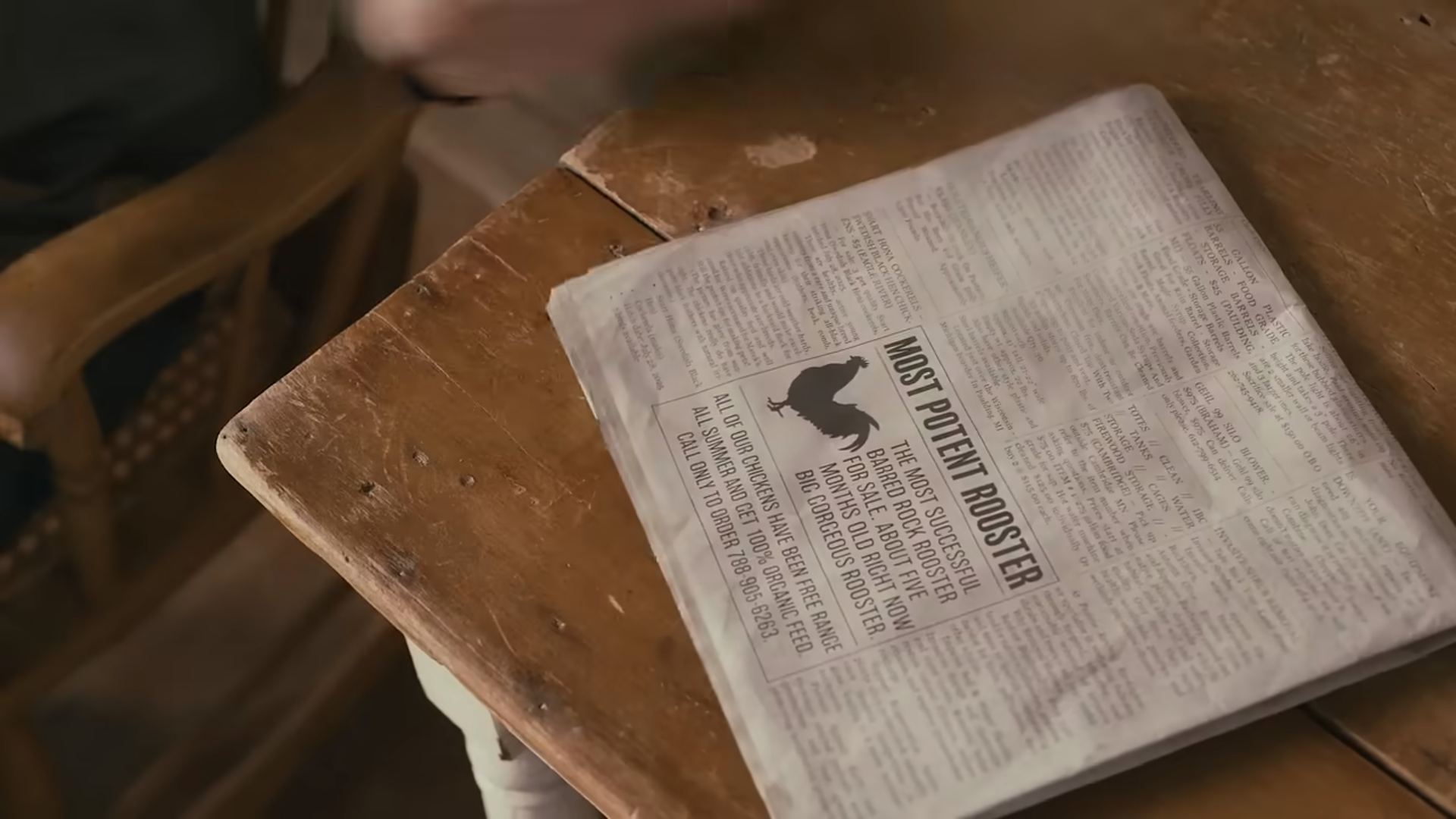 Most Potent Rooster classified ad in local newspaper, folded in half on a wooden table