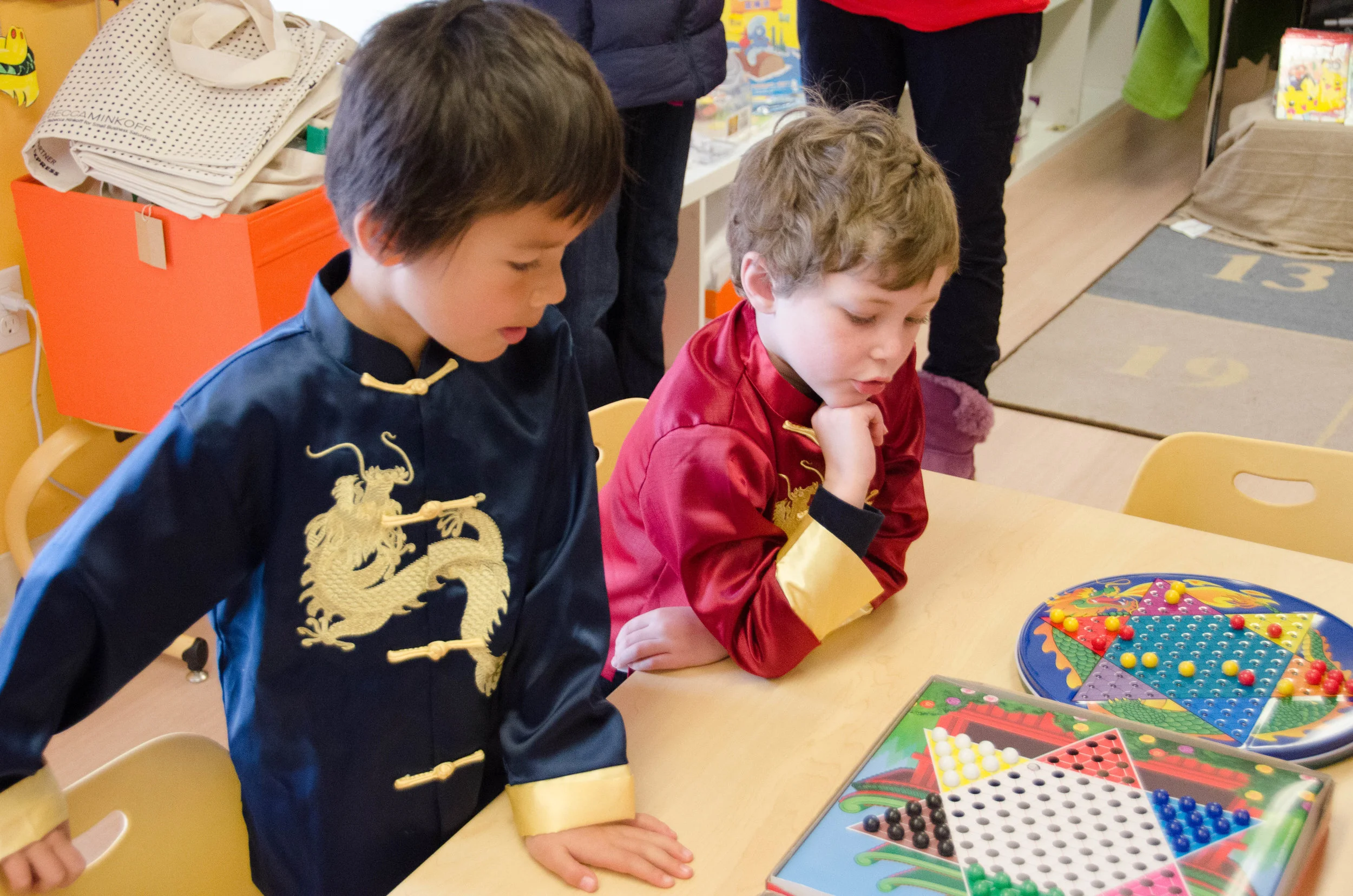 Two kindergarteners playing Chinese checkers in an activity room.
