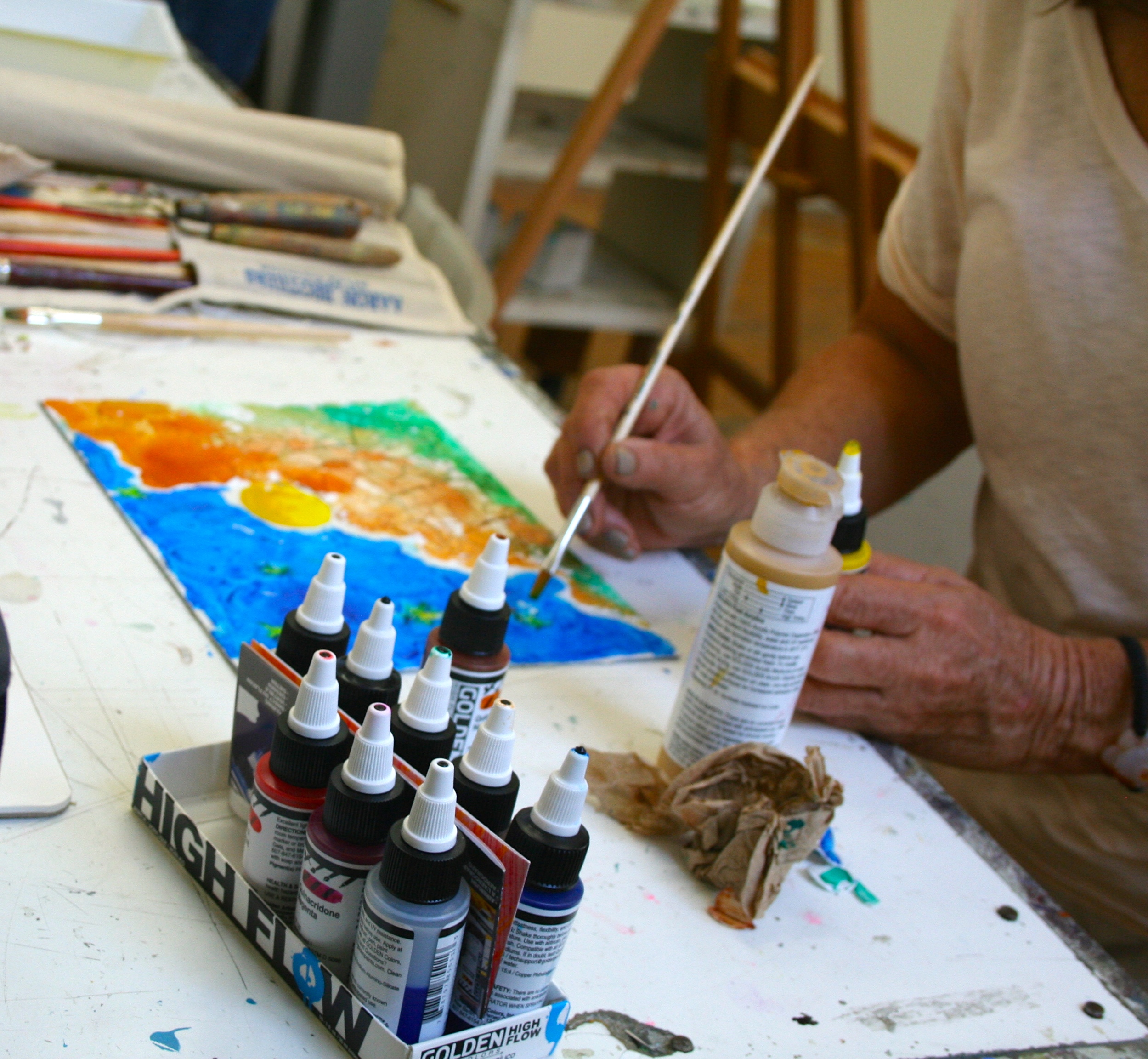 Here a student is using both Fluid and High Flow Acrylics by Golden to create her landscape painting.