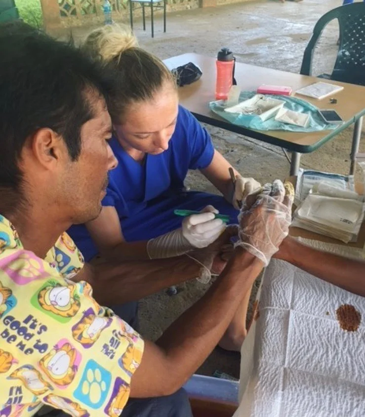 Lead Medical Provider, Luis, and Dr. Zimmerman carefully remove debris from a patient's wound to prevent infection. 