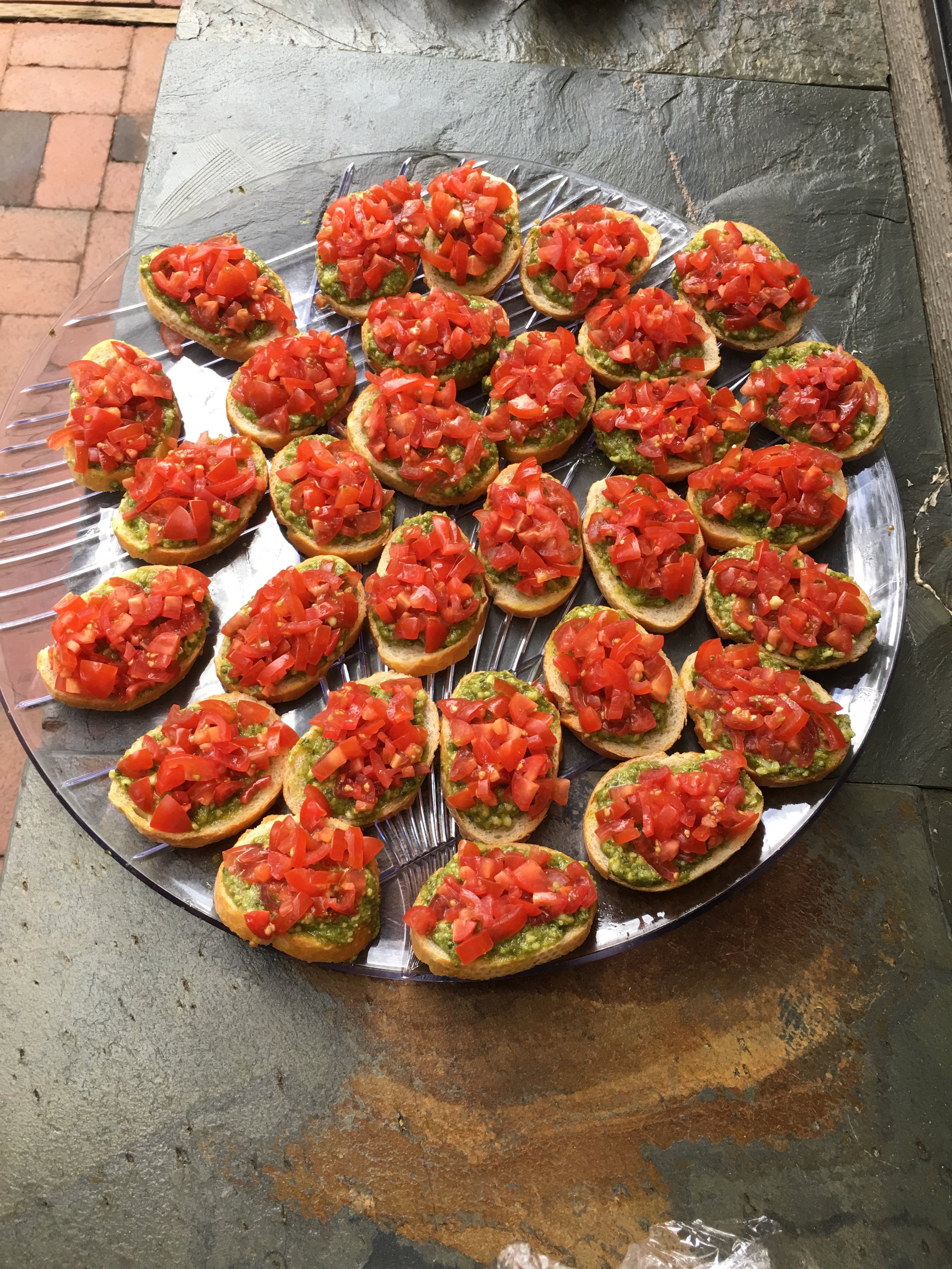 Bruschetta topped with pesto, and diced tomatoes.