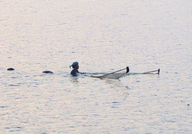 Just before dawn fisherman walk through the water with huge nets