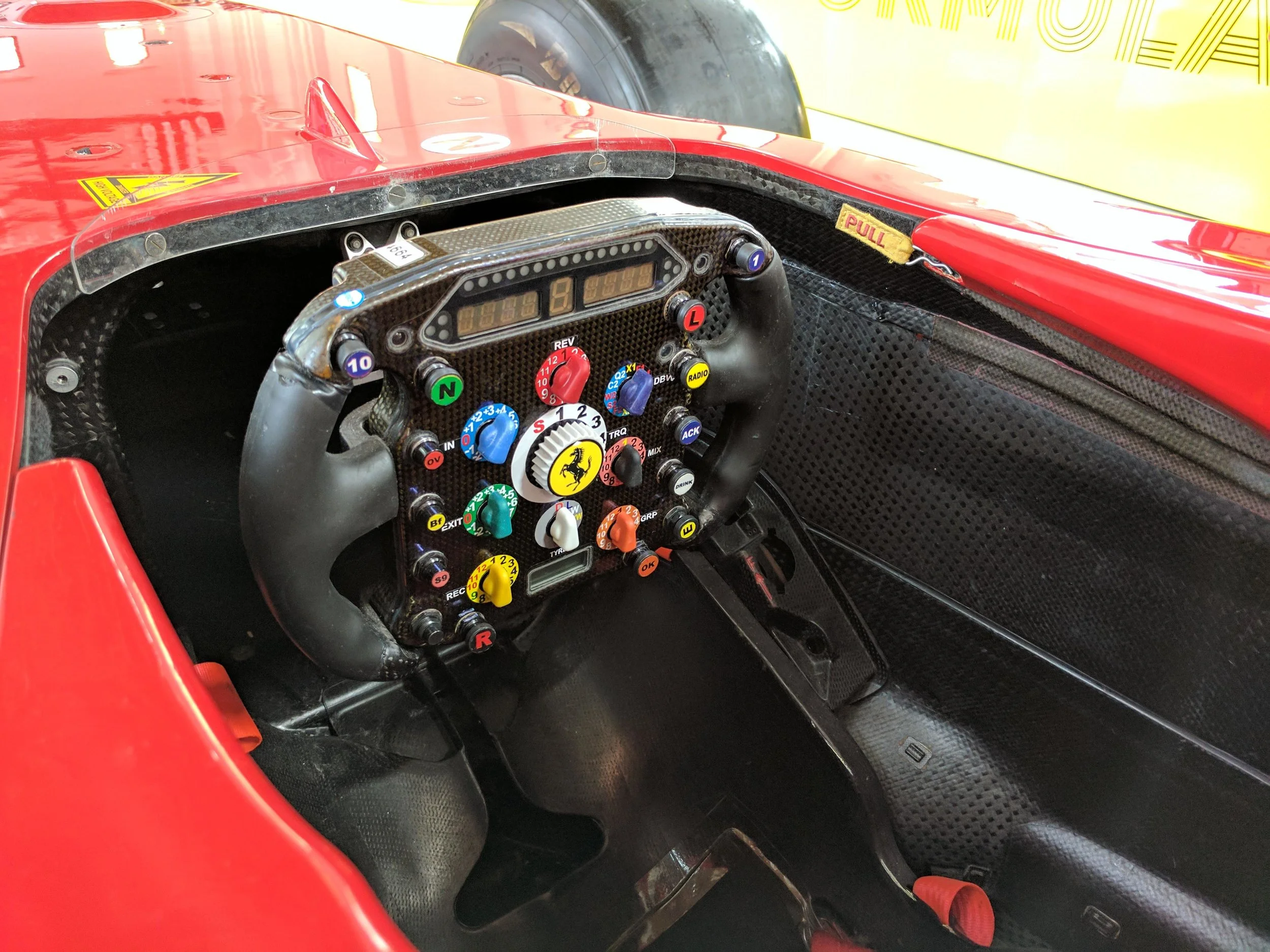 An old style steering wheel. Not as complicated as the ones today. And a pit board for the current team. 