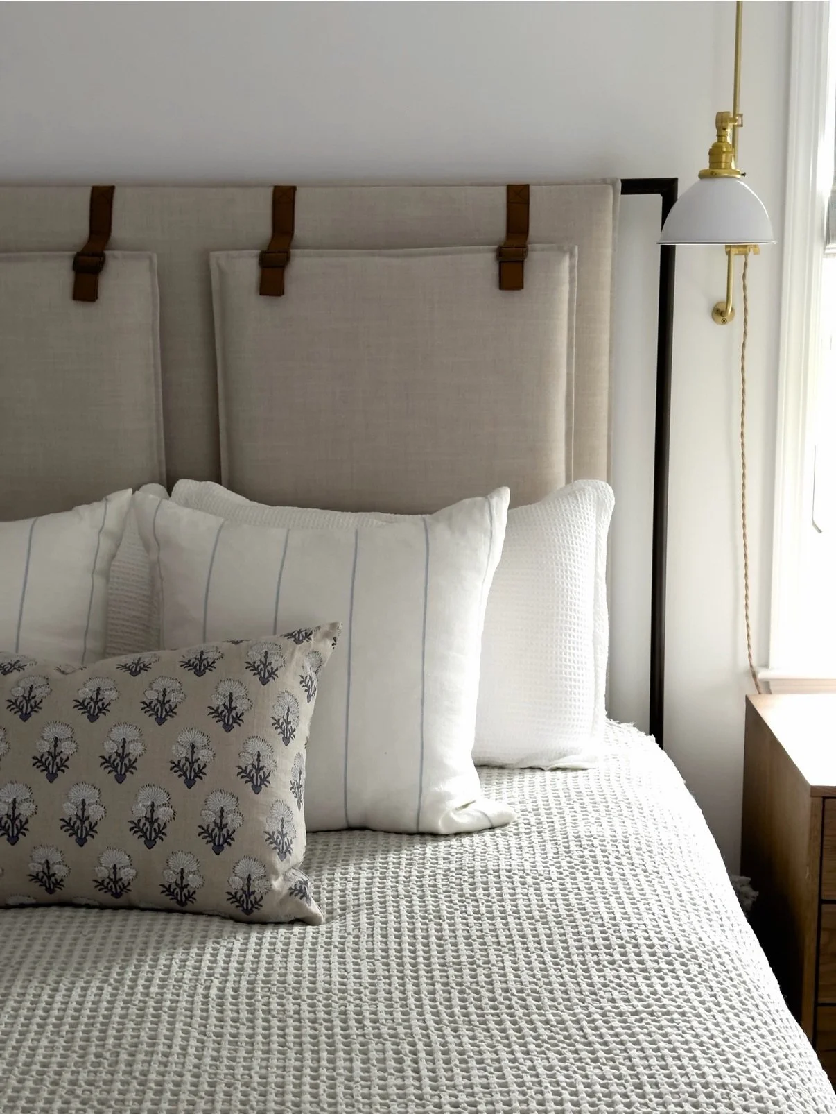 Sleep-in Saturday officially enacted. 😴 At #DaisysNewDigs, this guest room feels like a boutique hotel escape. Leather-tab linen headboard, antique brass swing-arm sconces, warm wood nightstands, and a pair of luggage racks that say come stay a whil